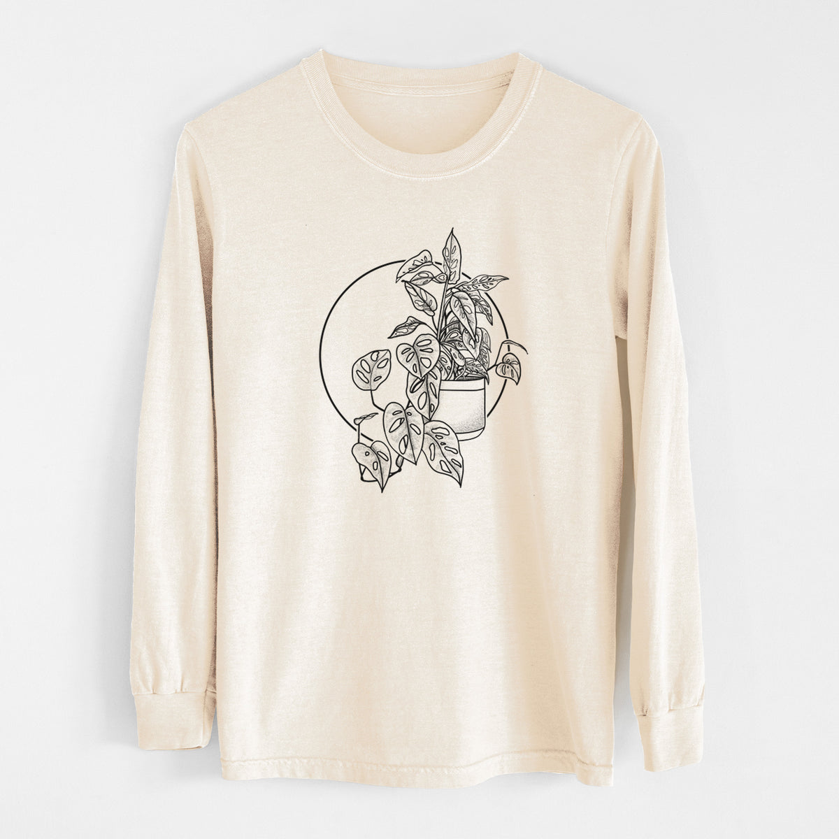 Ivory Comfort Colors long sleeve shirt laid flat, printed with a black ink illustration of a potted Monsteradansonii plant with trailing vines in front of a circle.