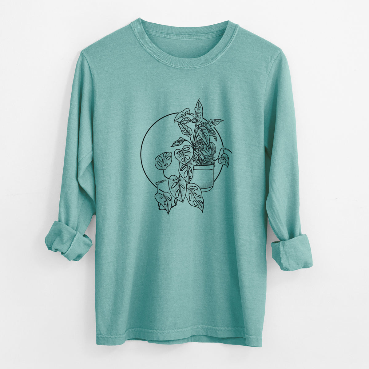 Reef green Comfort Colors long sleeve shirt laid flat with the cuffs rolled, printed with a black ink illustration of a potted Monsteradansonii plant with trailing vines in front of a circle.