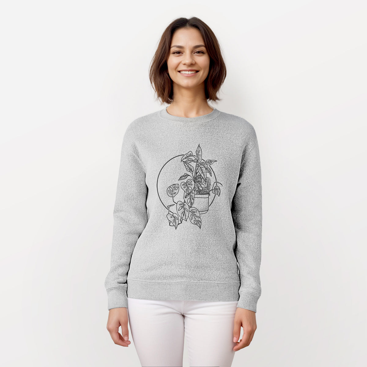 Woman wearing a knit sweatshirt printed with a black ink illustration of a potted Monsteradansonii plant with trailing vines in front of a circle.