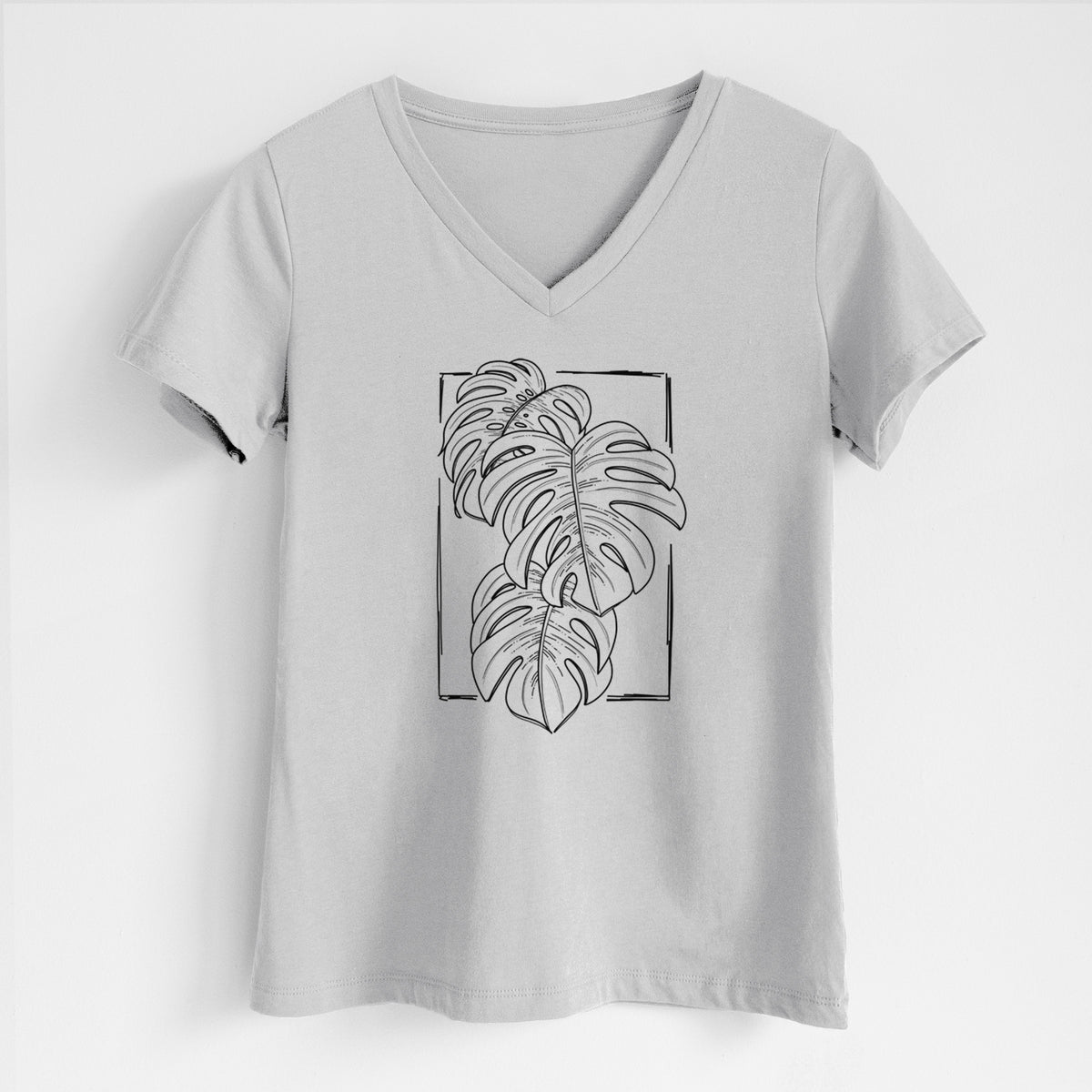Lunar grey women's relaxed fit cotton V-neck t-shirt laid flat, printed with a black ink line drawing of Monstera deliciosa leaves inside a rectangle outline.