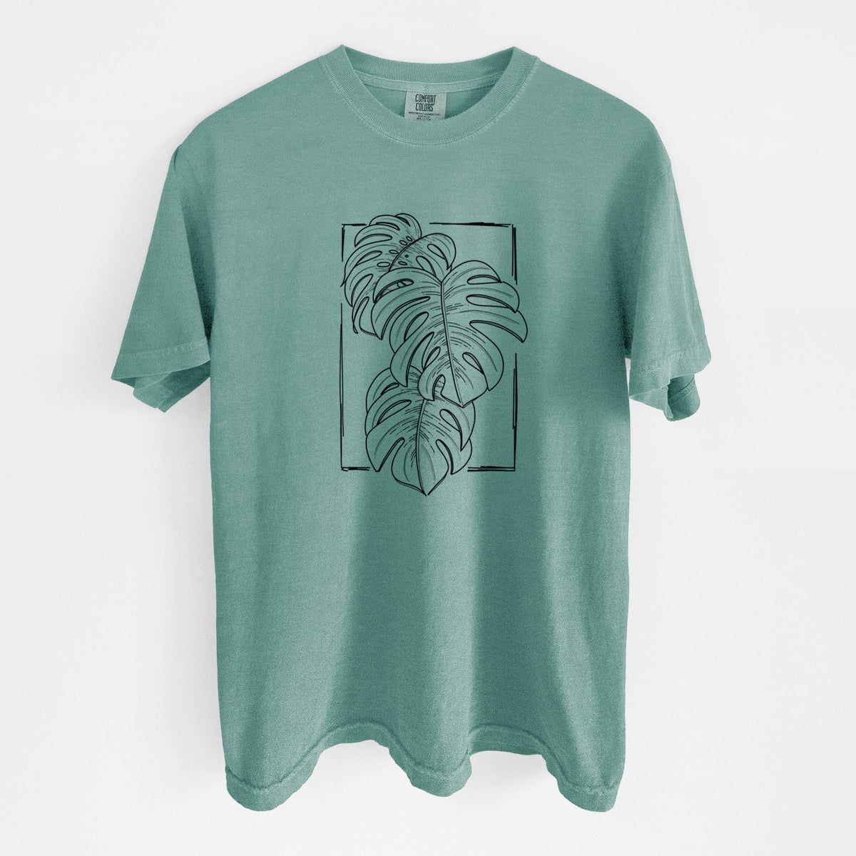 Reef green Comfort Colors t-shirt laid flat, printed with a black ink line drawing of Monstera deliciosa leaves inside a rectangle outline.