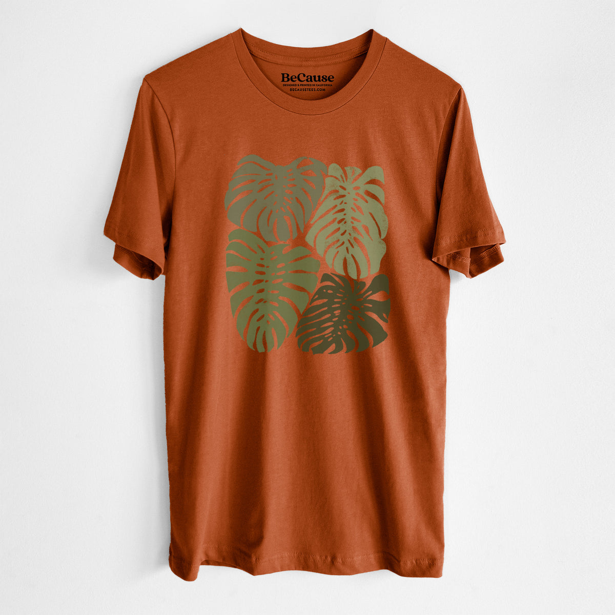 Autumn lightweight cotton t-shirt laid flat, printed with a full-color illustration of large green Monstera leaves filling a square.