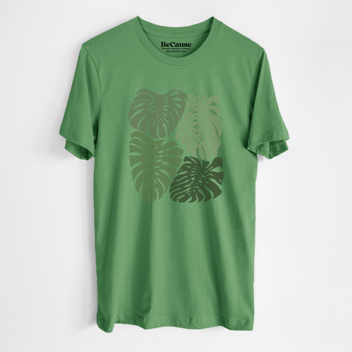 Leaf green lightweight cotton t-shirt laid flat, printed with a full-color illustration of large green Monstera leaves filling a square.