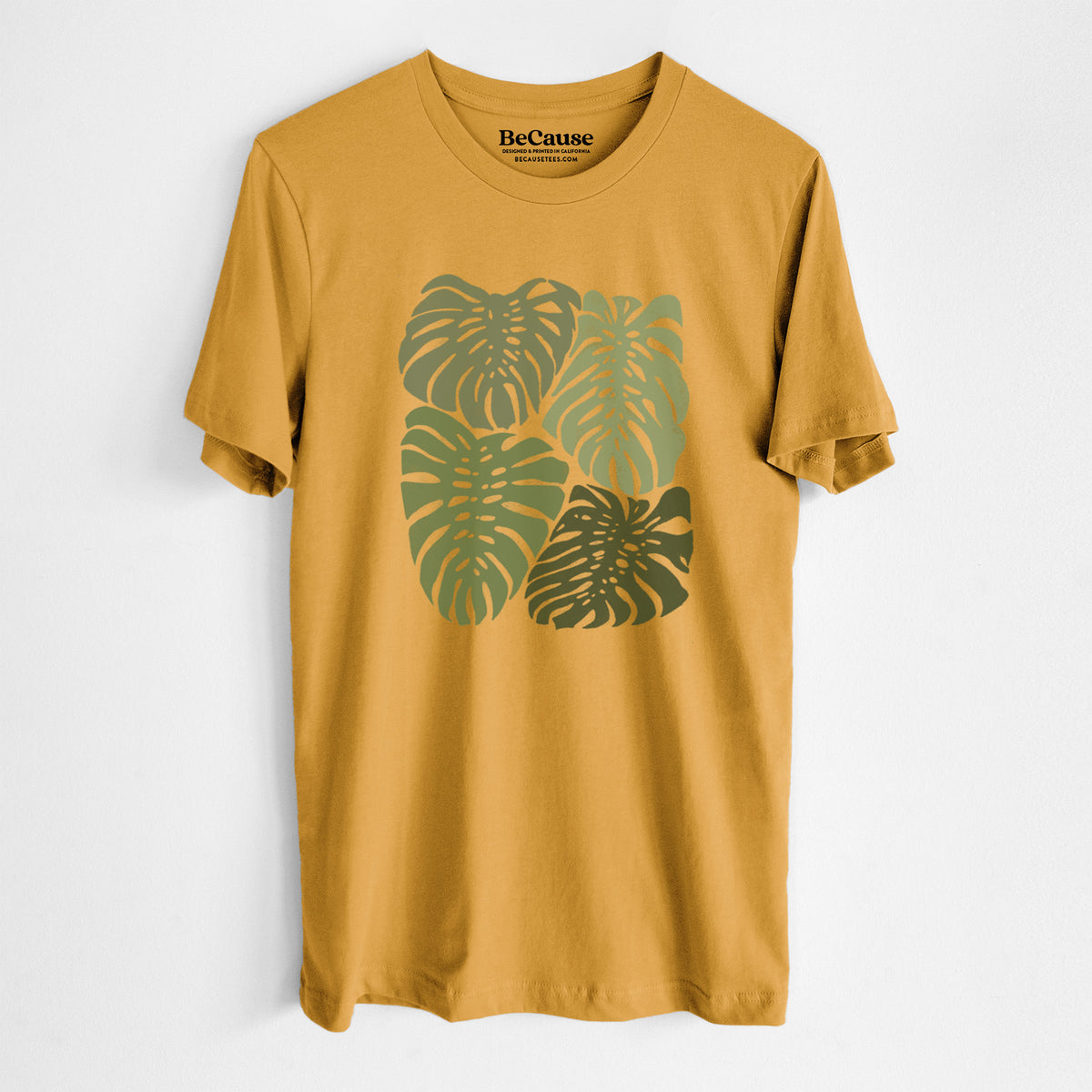 Mustard yellow lightweight cotton t-shirt laid flat, printed with a full-color illustration of large green Monstera leaves filling a square.