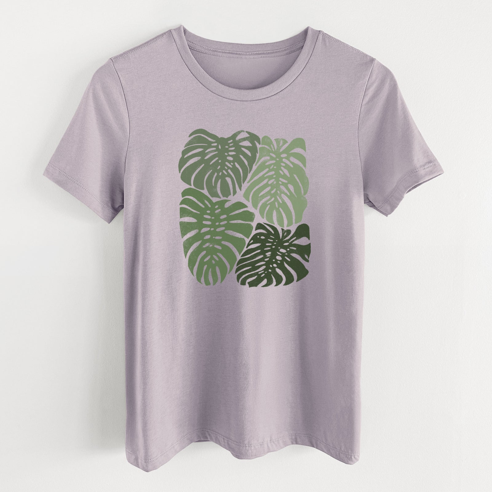Light violet women's relaxed fit cotton t-shirt laid flat, printed with a full-color illustration of large green Monstera leaves filling a square.