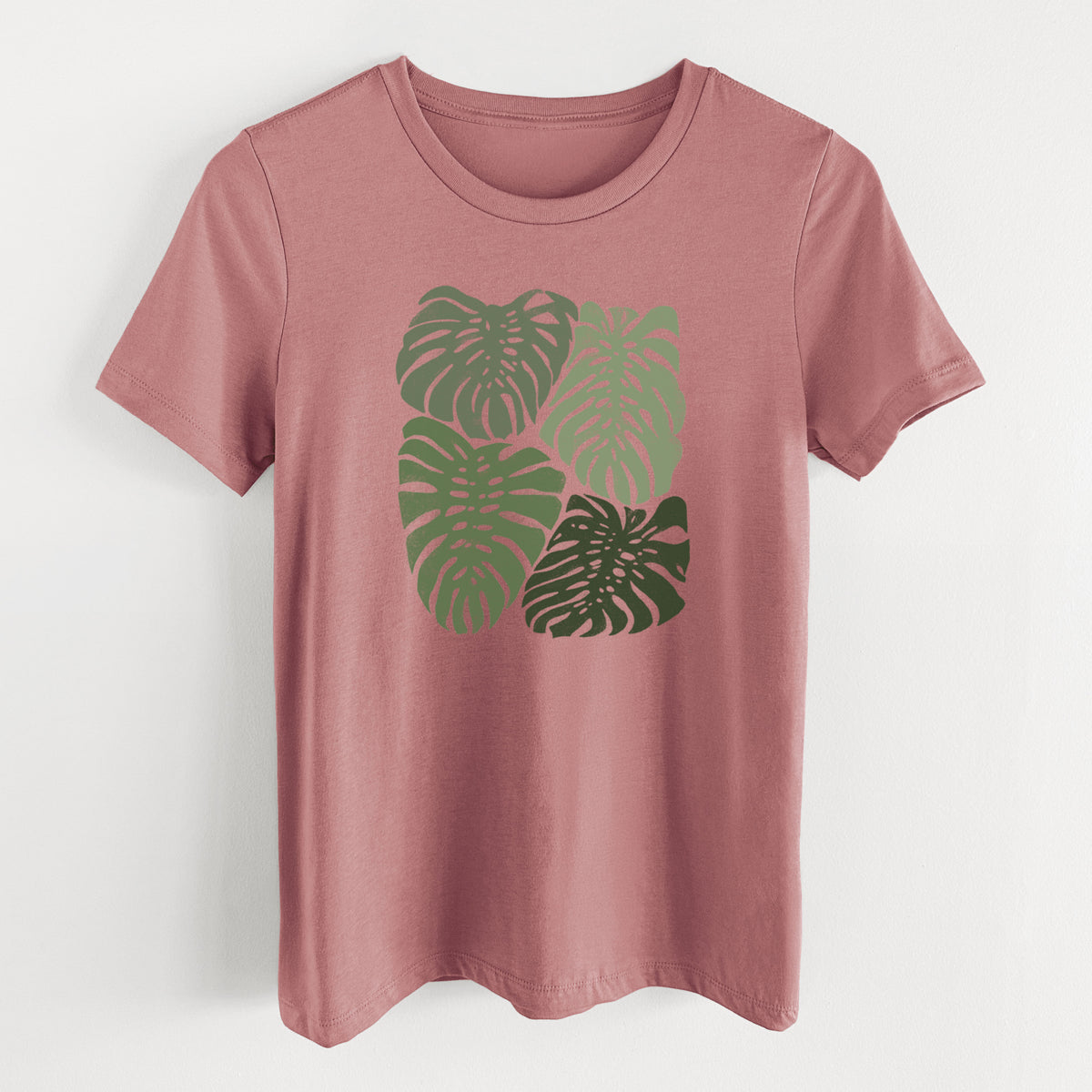 Mauve pink women's relaxed fit cotton t-shirt laid flat, printed with a full-color illustration of large green Monstera leaves filling a square.