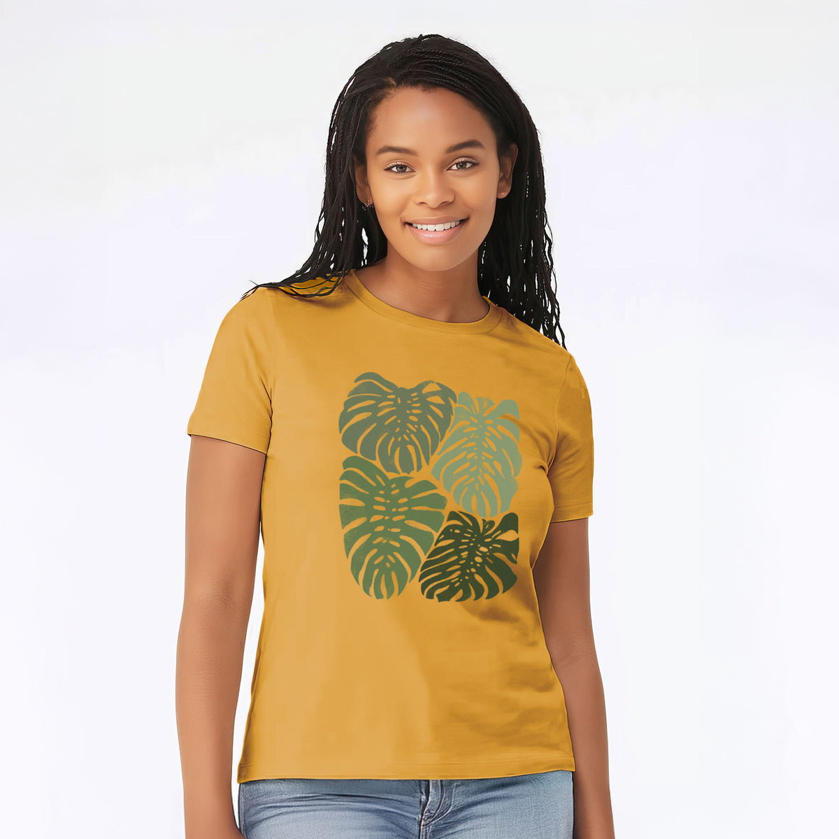 Woman wearing a mustard yellow women's relaxed fit cotton t-shirt printed with a full-color illustration of large green Monstera leaves filling a square.