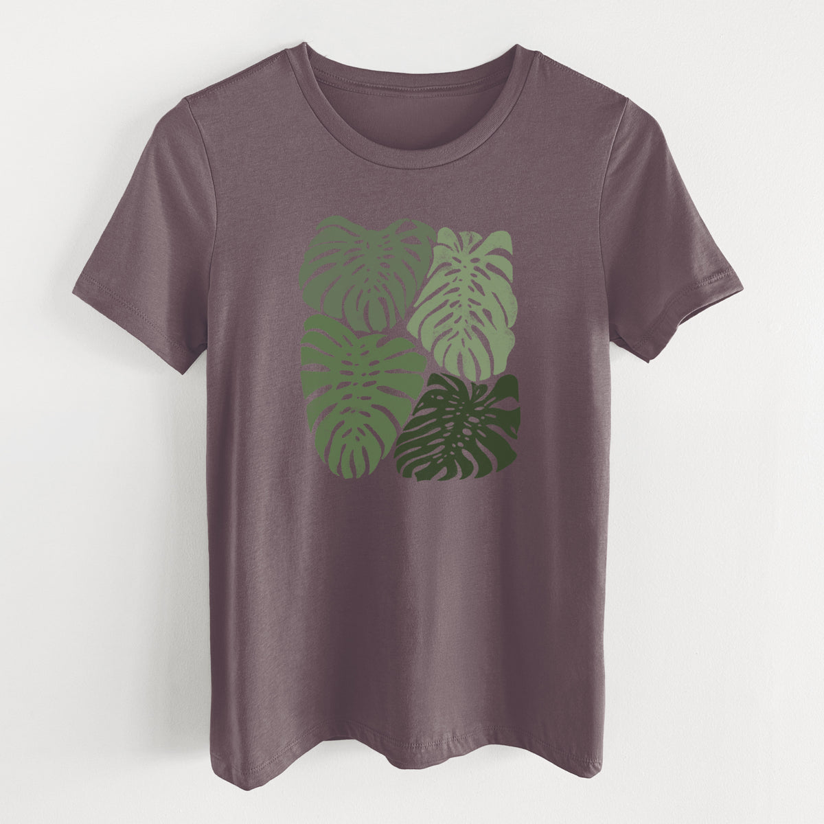 Purple storm women's relaxed fit cotton t-shirt laid flat, printed with a full-color illustration of large green Monstera leaves filling a square.