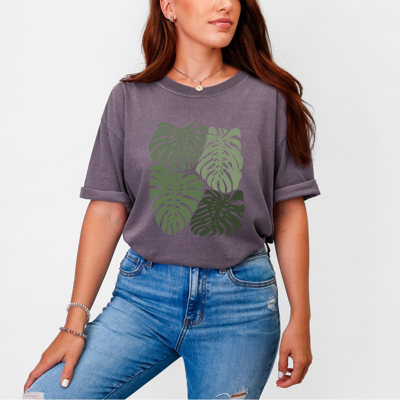 Blue jean Comfort Colors t-shirt laid flat, printed with a full-color illustration of large green Monstera leaves filling a square.
