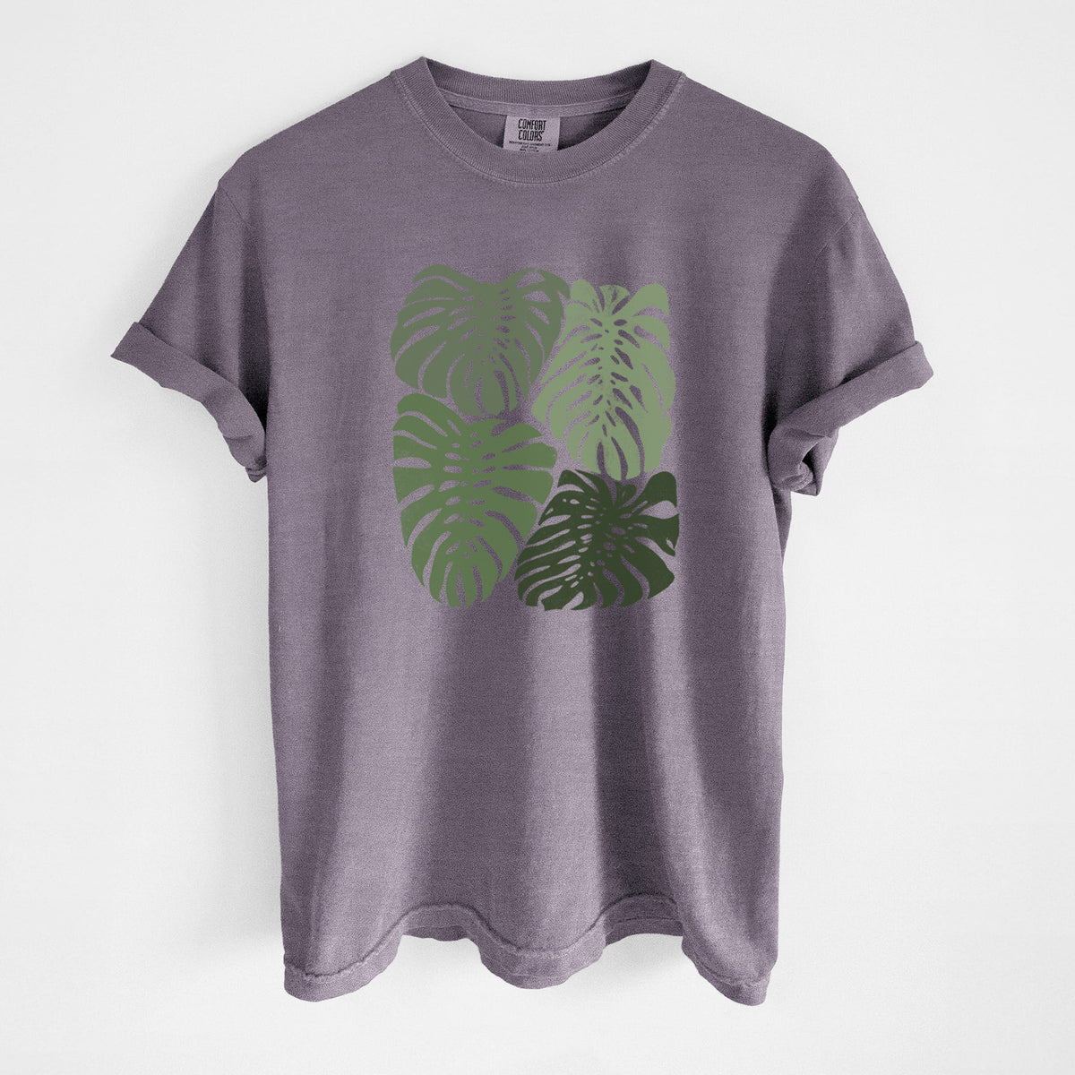 Wine red Comfort Colors t-shirt laid flat, printed with a full-color illustration of large green Monstera leaves filling a square.