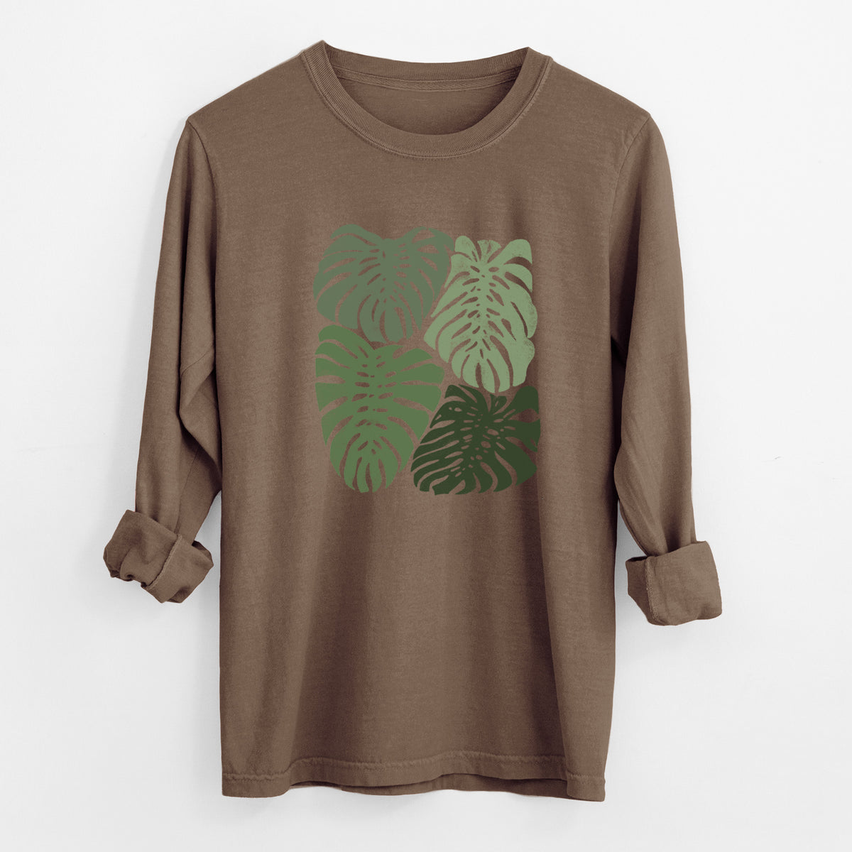 Espresso brown Comfort Colors long sleeve shirt laid flat with the cuffs rolled, printed with a full-color illustration of large green Monstera leaves filling a square.
