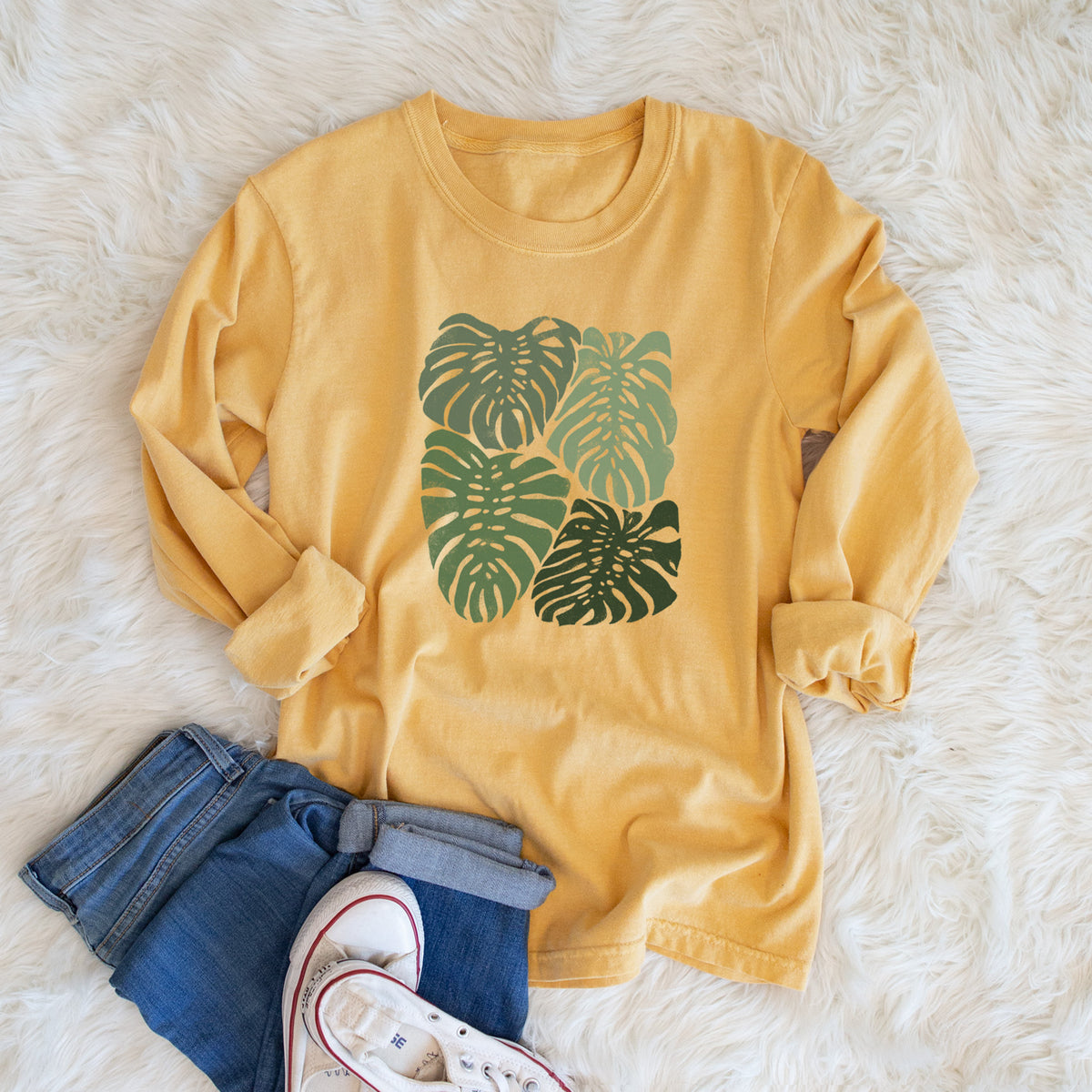 Golden wheat yellow Comfort Colors long sleeve shirt printed with a full-color illustration of large green Monstera leaves filling a square, shown in a lifestyle photo.