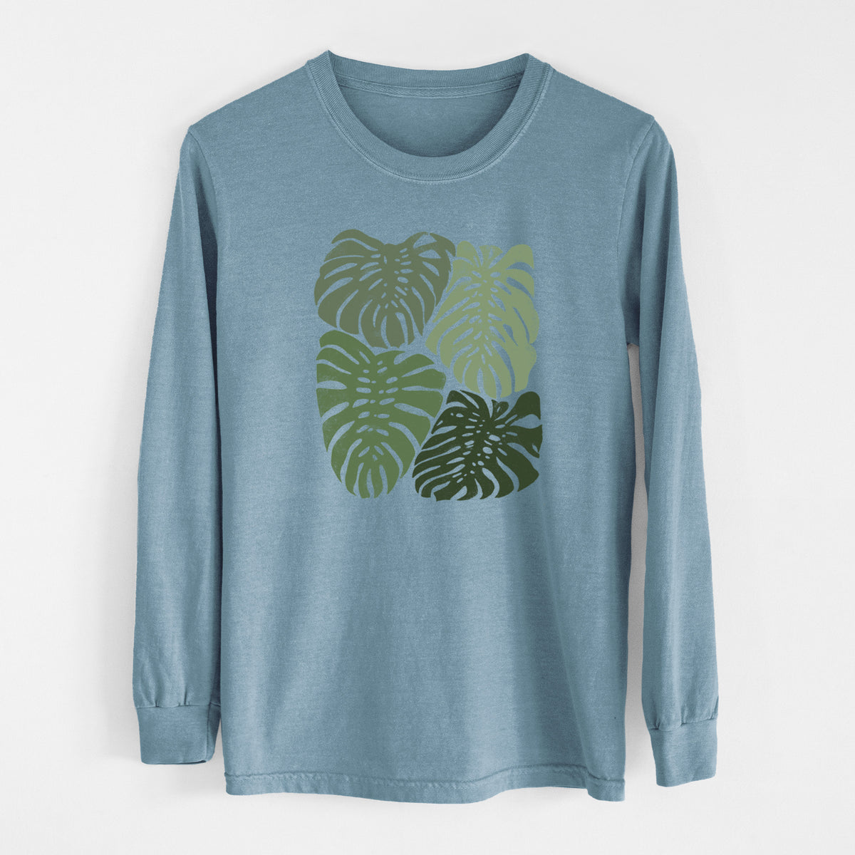 Steel blue Comfort Colors long sleeve shirt laid flat, printed with a full-color illustration of large green Monstera leaves filling a square.