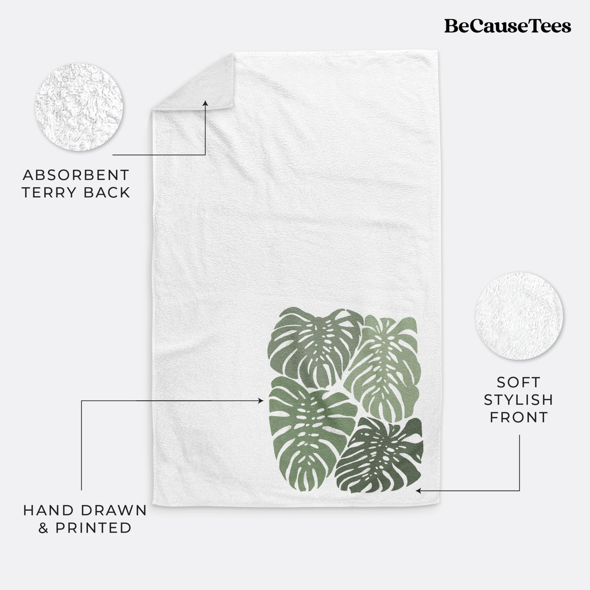 White hand towel printed with a full-color illustration of large green Monstera leaves filling a square.