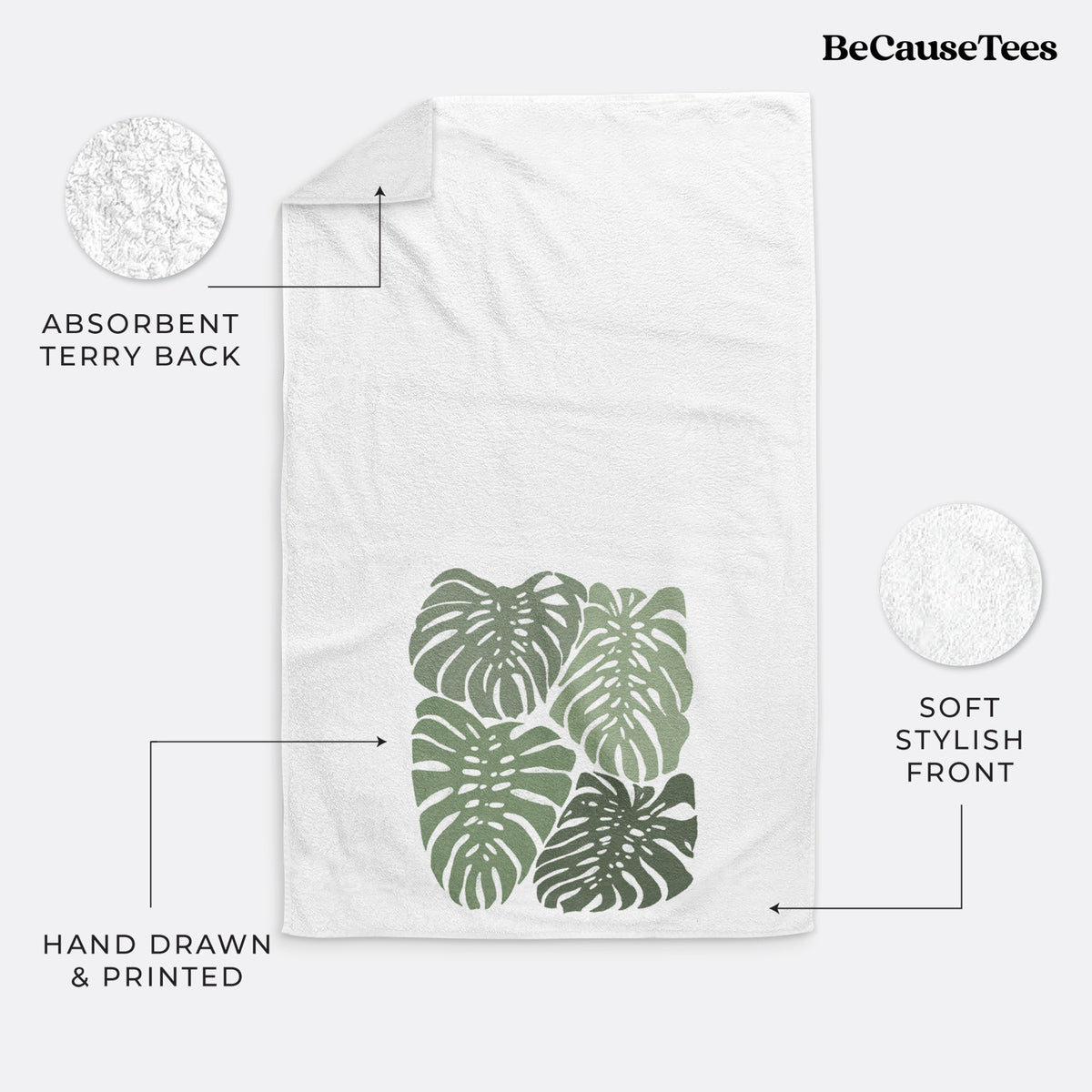 White hand towel printed with a full-color illustration of large green Monstera leaves filling a square.