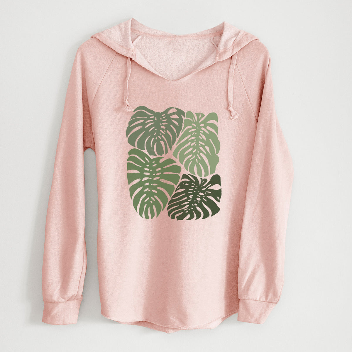 Blush pink women's Cali Wave hooded sweatshirt laid flat, printed with a full-color illustration of large green Monstera leaves filling a square.