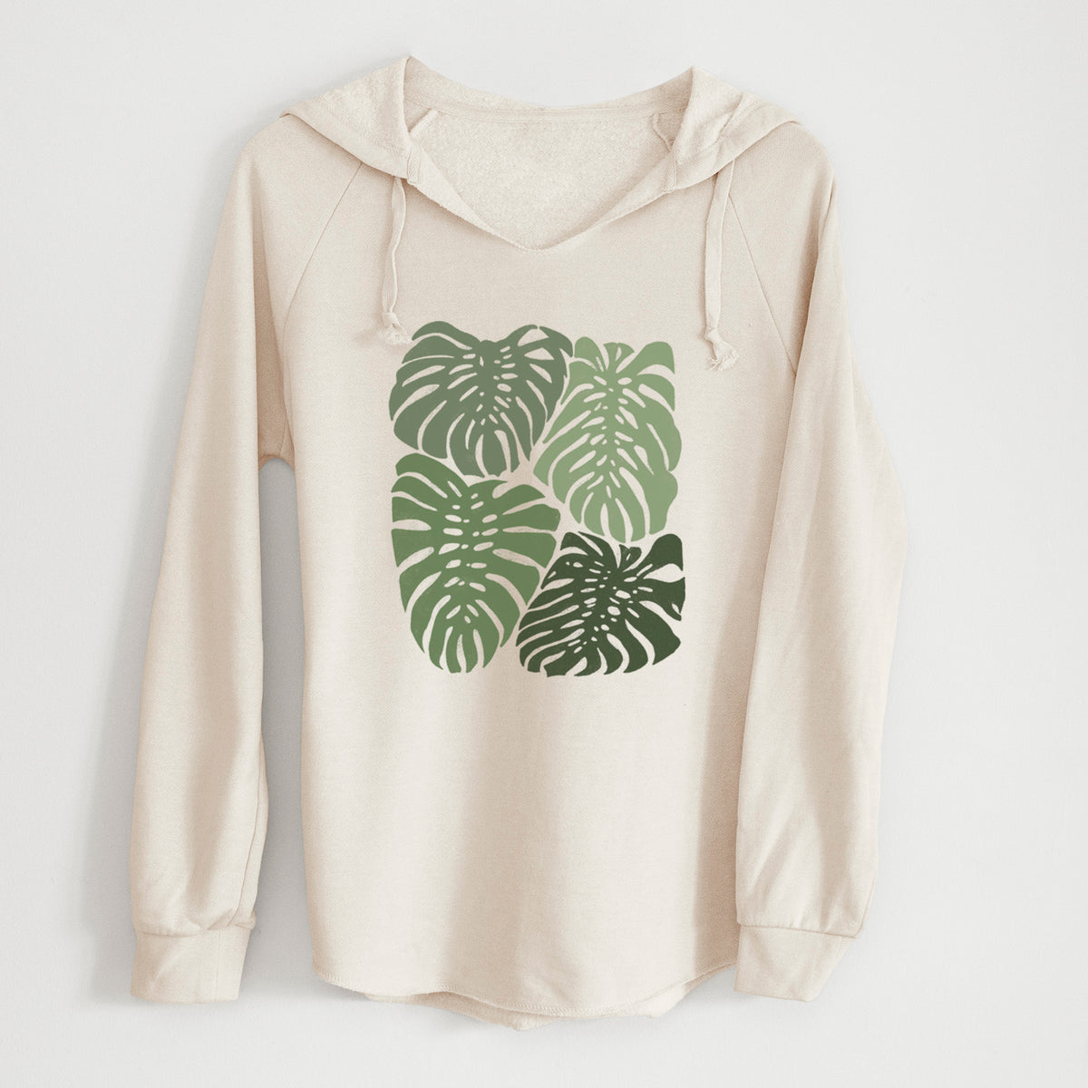 Bone cream women's Cali Wave hooded sweatshirt laid flat, printed with a full-color illustration of large green Monstera leaves filling a square.