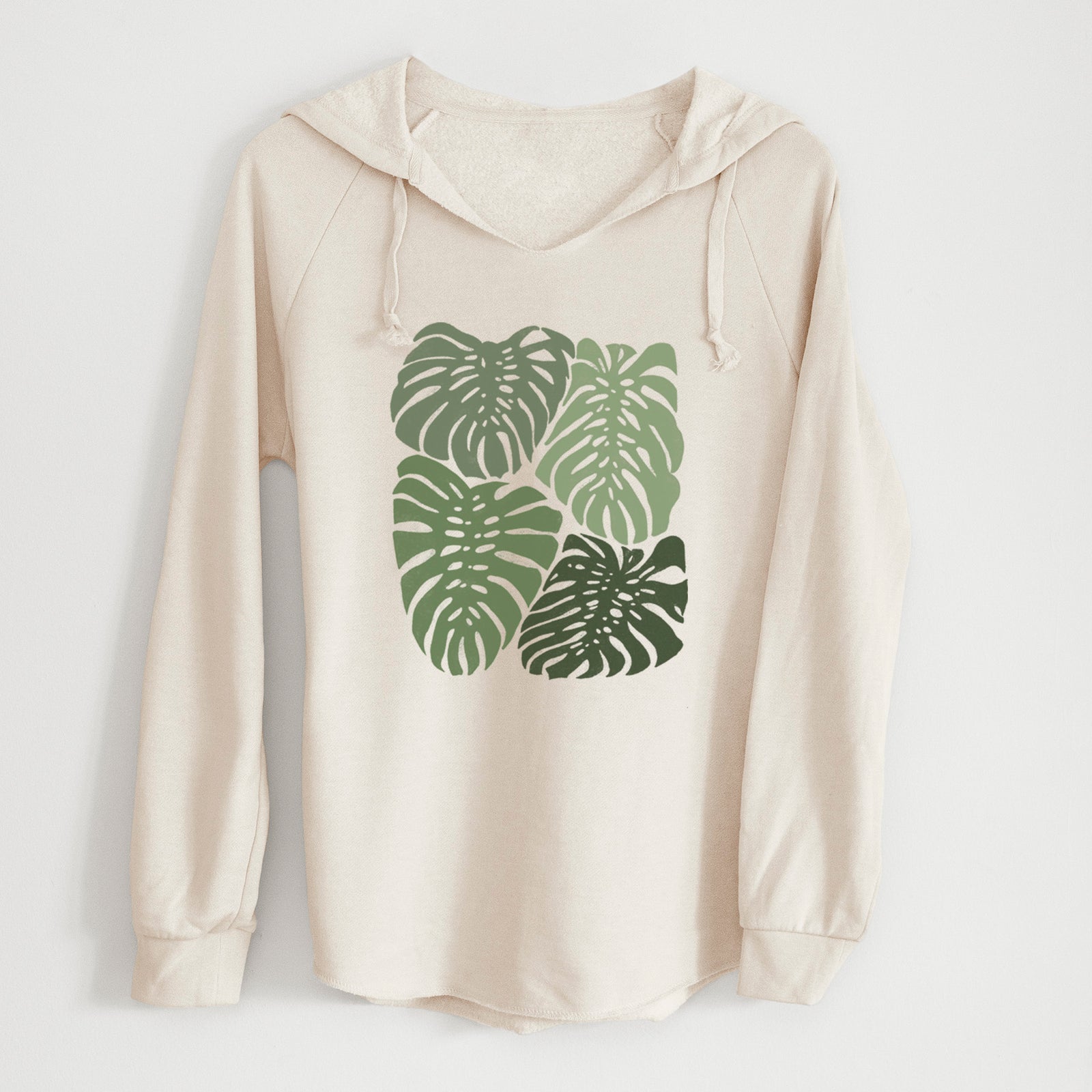 Bone cream women's Cali Wave hooded sweatshirt laid flat, printed with a full-color illustration of large green Monstera leaves filling a square.
