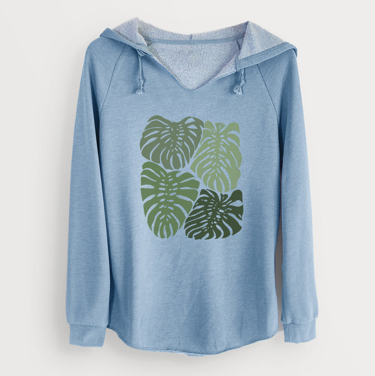 Misty blue women's Cali Wave hooded sweatshirt laid flat, printed with a full-color illustration of large green Monstera leaves filling a square.