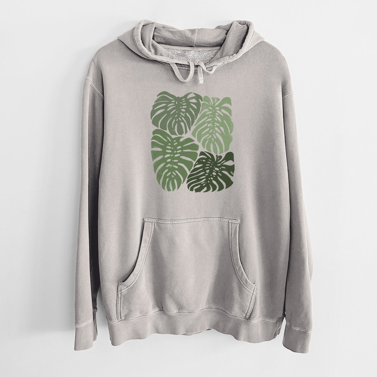 Cement grey pigment dyed hoodie laid flat, printed with a full-color illustration of large green Monstera leaves filling a square.