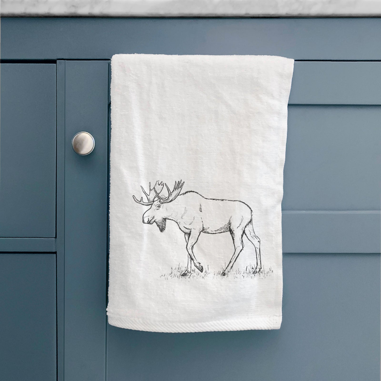 White hand towel printed with a black ink illustration of a bull moose with broad antlers walking.