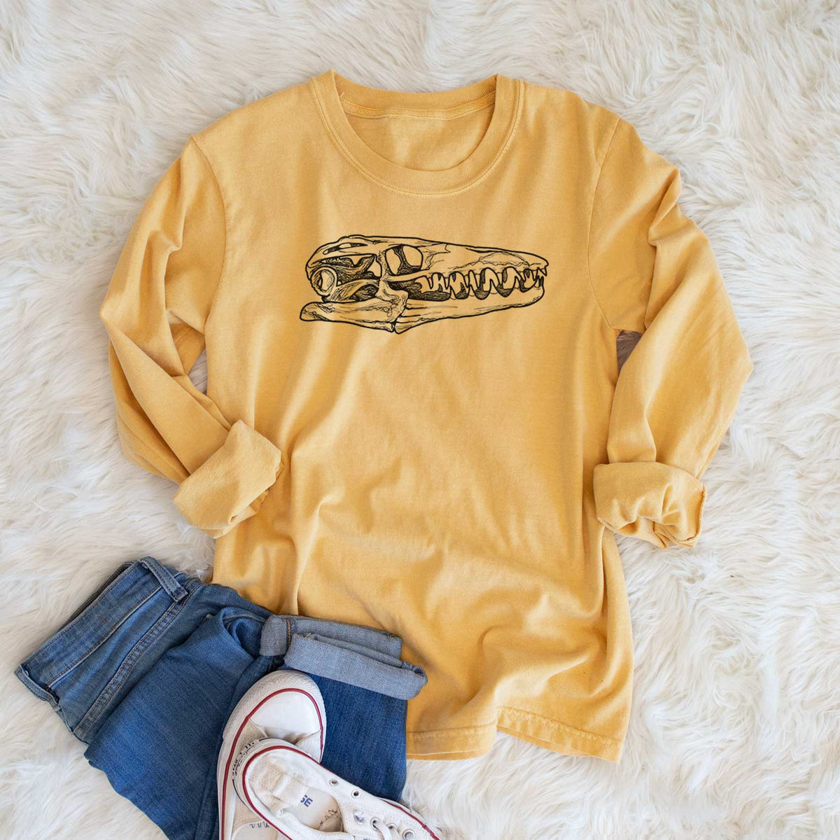 Golden wheat yellow Comfort Colors long sleeve shirt printed with a detailed black ink illustration of a Mosasaur skull, shown in a lifestyle photo.