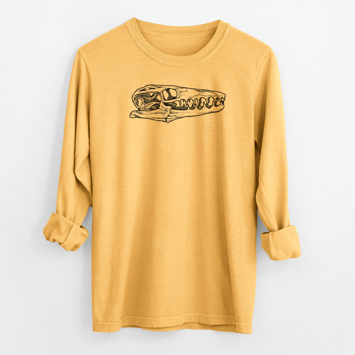 Golden wheat yellow Comfort Colors long sleeve shirt laid flat with the cuffs rolled, printed with a detailed black ink illustration of a Mosasaur skull.