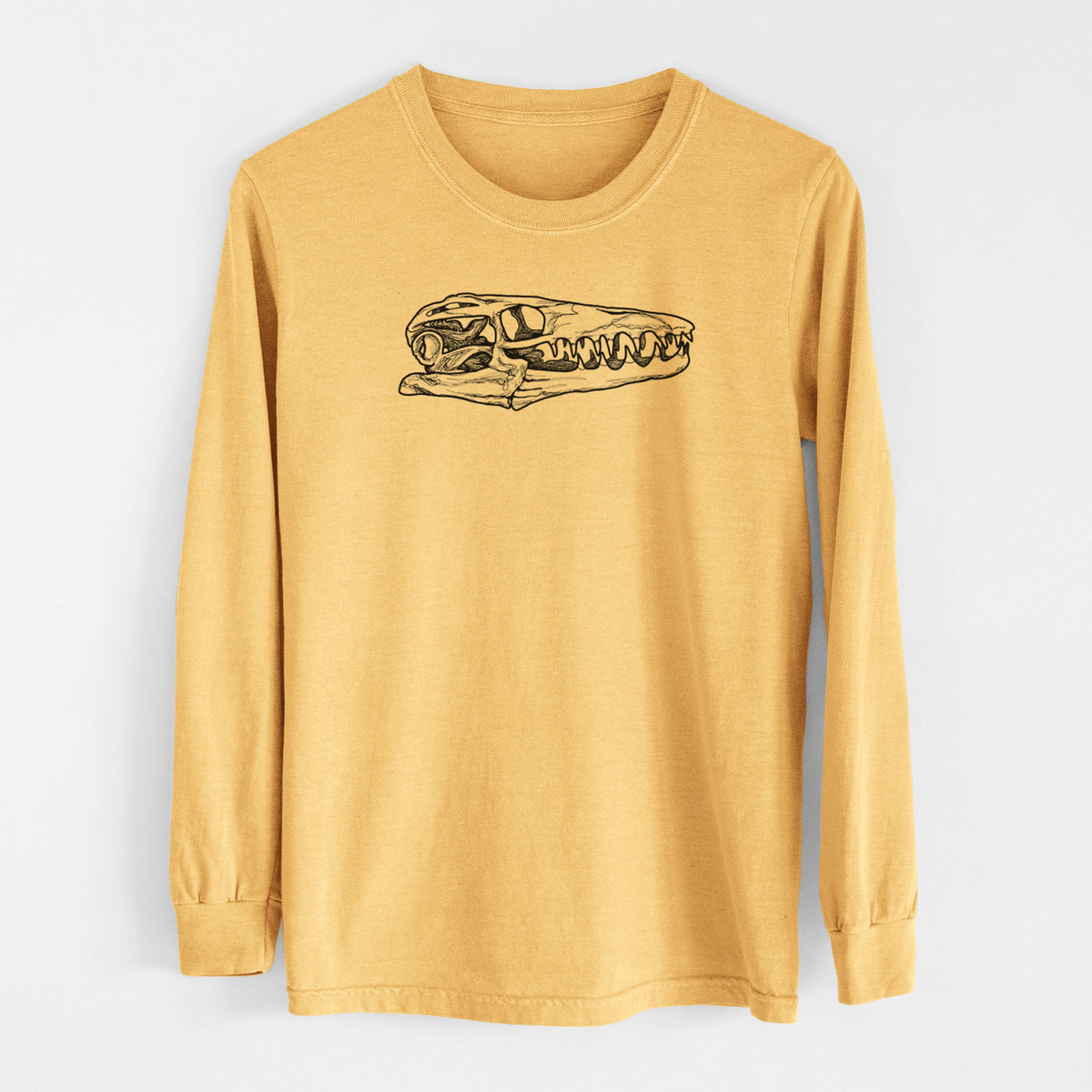 Golden wheat yellow Comfort Colors long sleeve shirt laid flat, printed with a detailed black ink illustration of a Mosasaur skull.