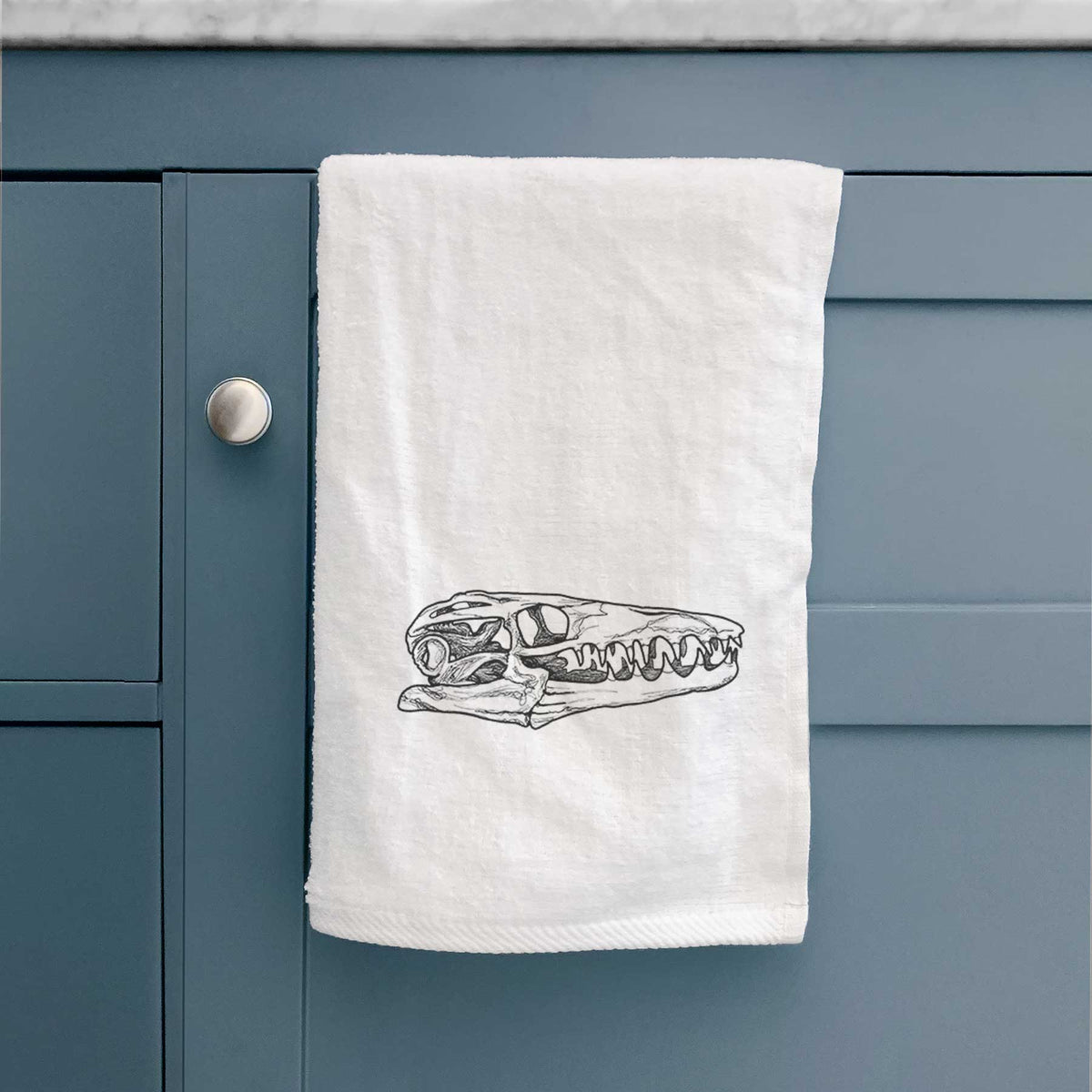 White hand towel printed with a detailed black ink illustration of a Mosasaur skull.