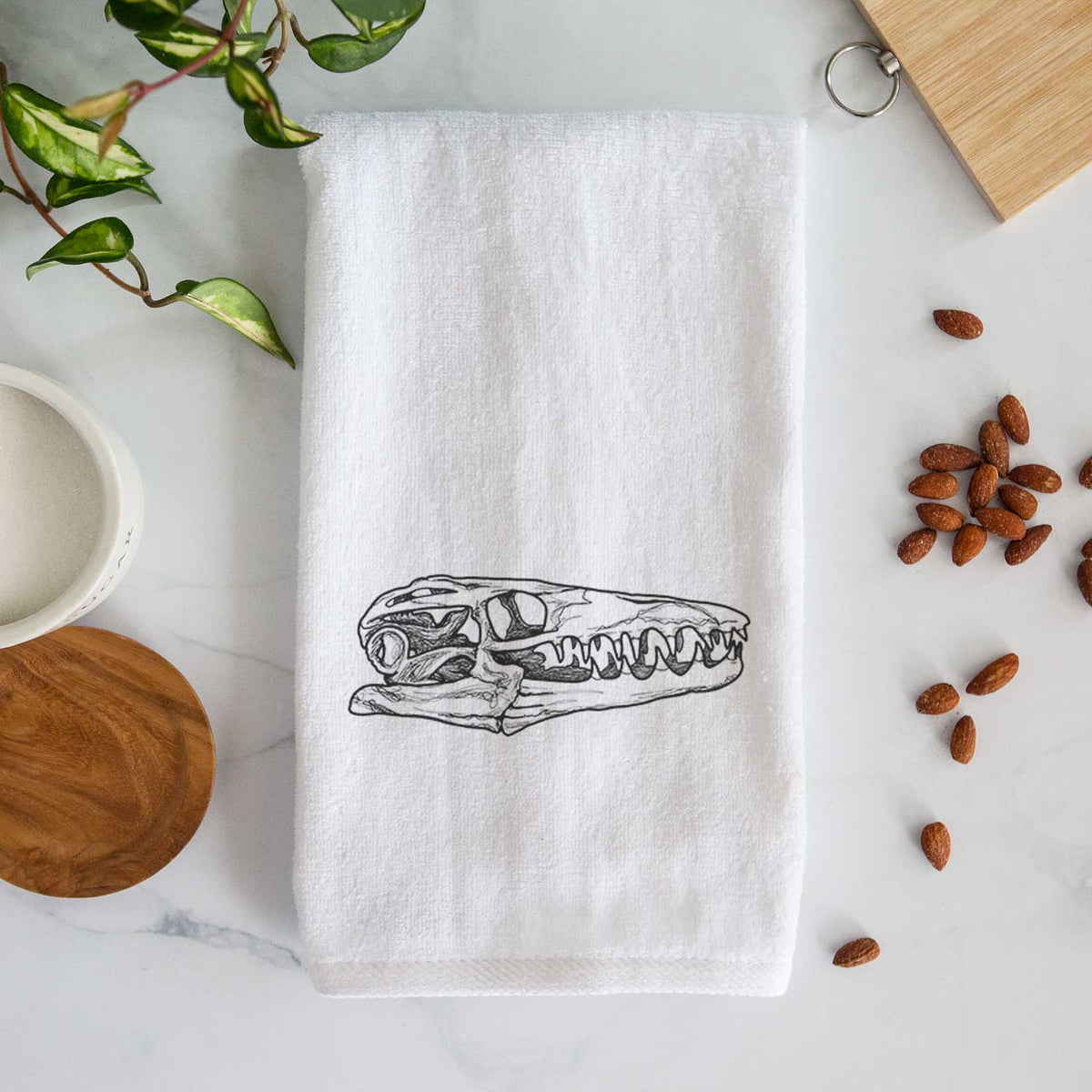 White hand towel printed with a detailed black ink illustration of a Mosasaur skull.