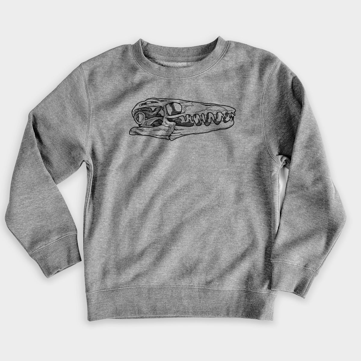 Nickel grey youth crewneck sweatshirt laid flat, printed with a detailed black ink illustration of a Mosasaur skull.