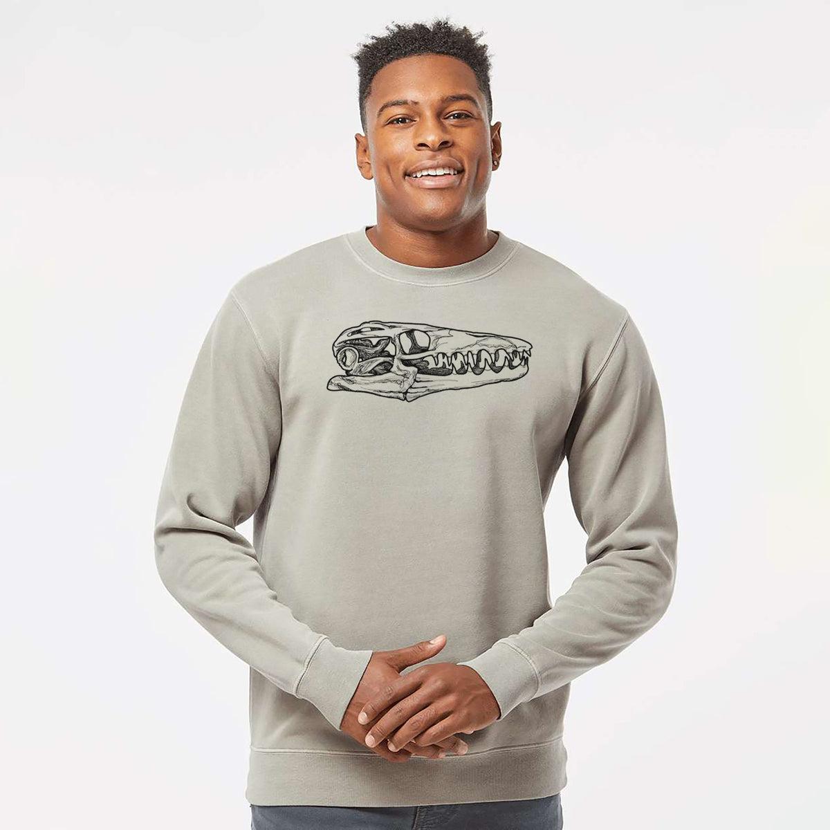 Model wearing a cement grey pigment dyed crewneck sweatshirt printed with a detailed black ink illustration of a Mosasaur skull.