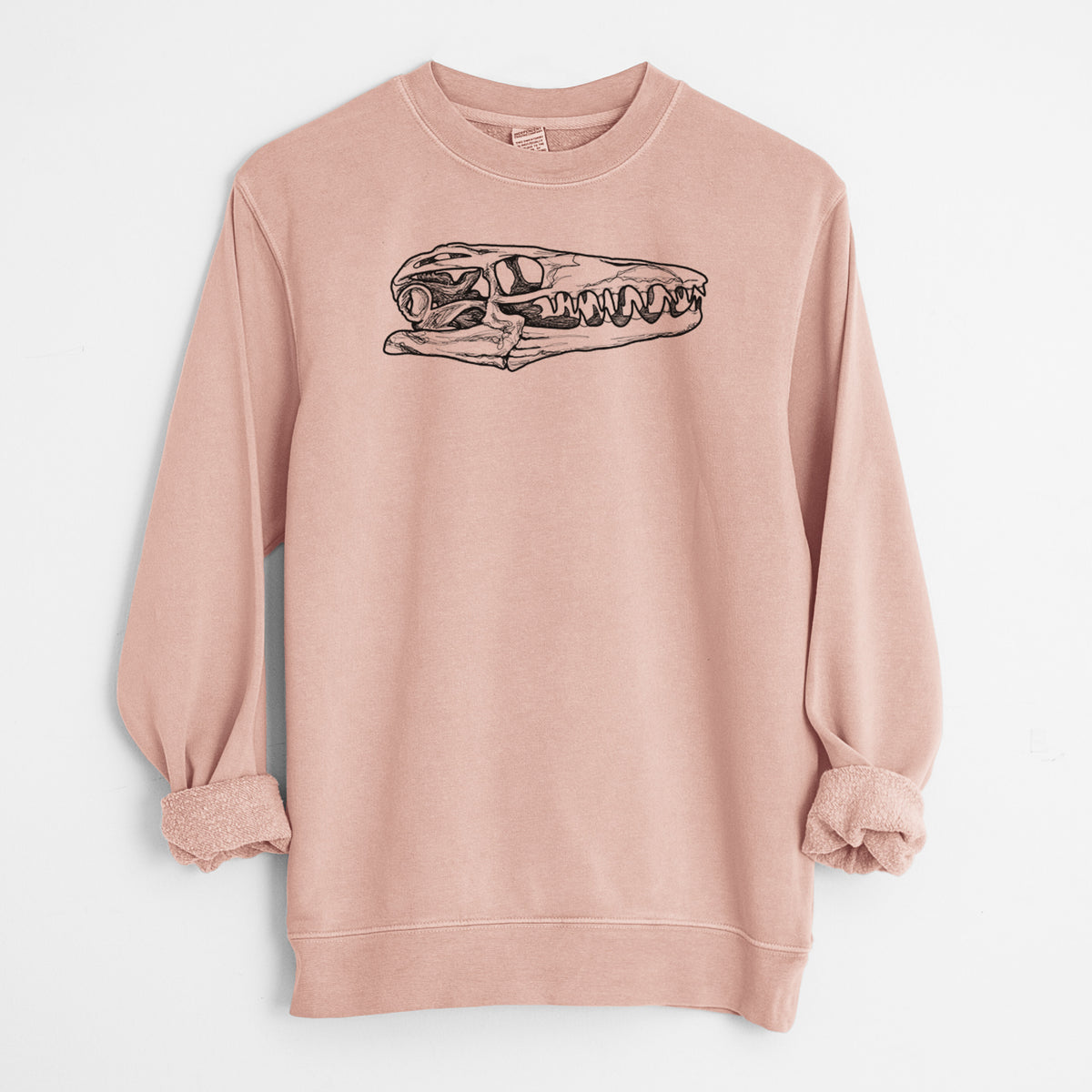 Dusty pink pigment dyed crewneck sweatshirt laid flat with the sleeves rolled, printed with a detailed black ink illustration of a Mosasaur skull.
