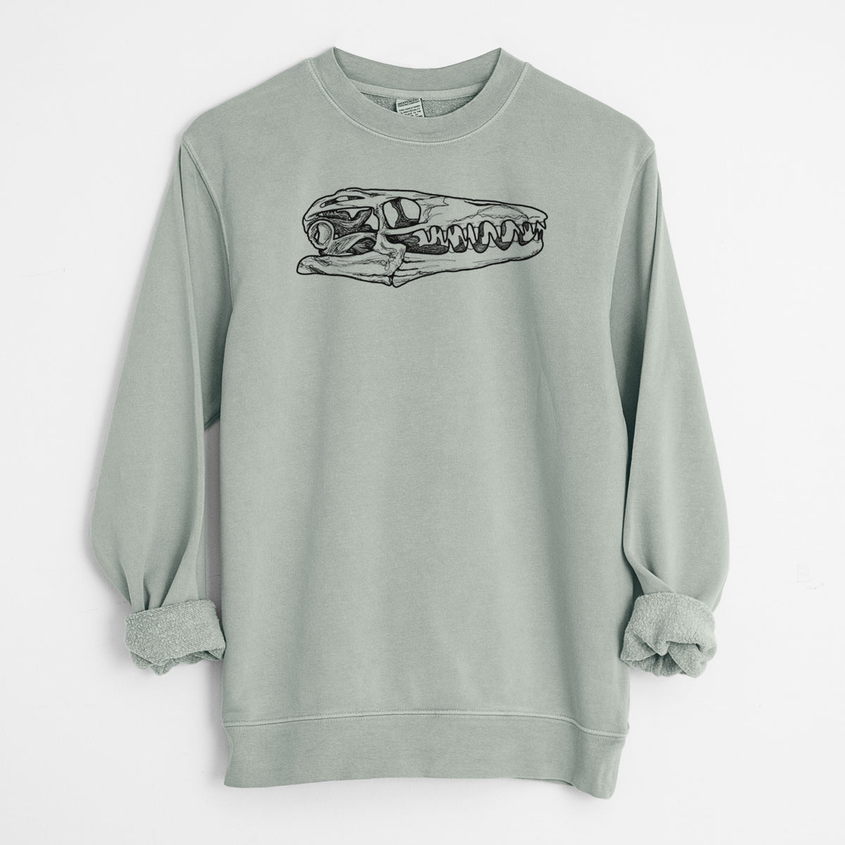 Sage green pigment dyed crewneck sweatshirt laid flat with the sleeves rolled, printed with a detailed black ink illustration of a Mosasaur skull.