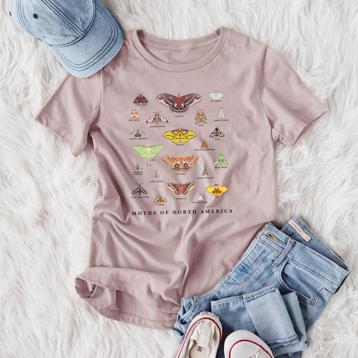 Women's relaxed fit cotton t-shirt printed with a full-color chart of North American moths, each labeled with its species, styled flat on a white faux fur rug with jeans.