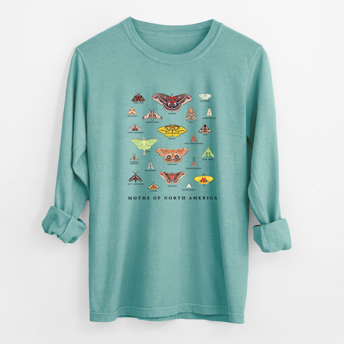 Reef green Comfort Colors long sleeve shirt laid flat with the cuffs rolled, printed with a full-color chart of North American moths, each labeled with its species.
