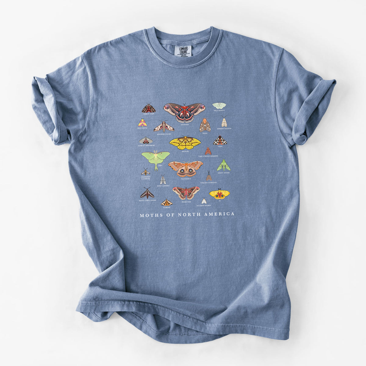 Blue jean Comfort Colors t-shirt laid flat, printed with a full-color chart of North American moths, each labeled with its species.
