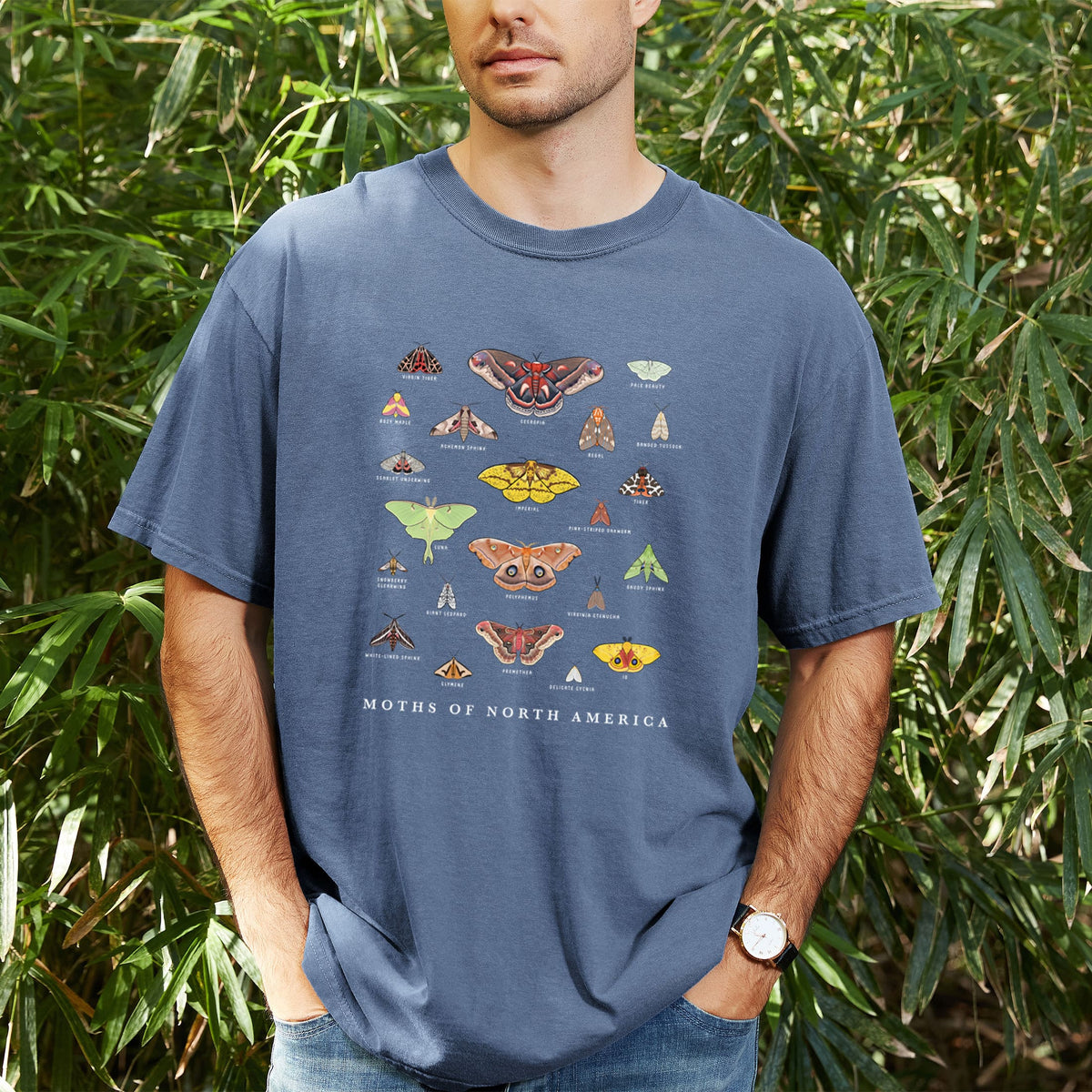 Man wearing a Comfort Colors t-shirt printed with a full-color chart of North American moths, each labeled with its species, outdoors.