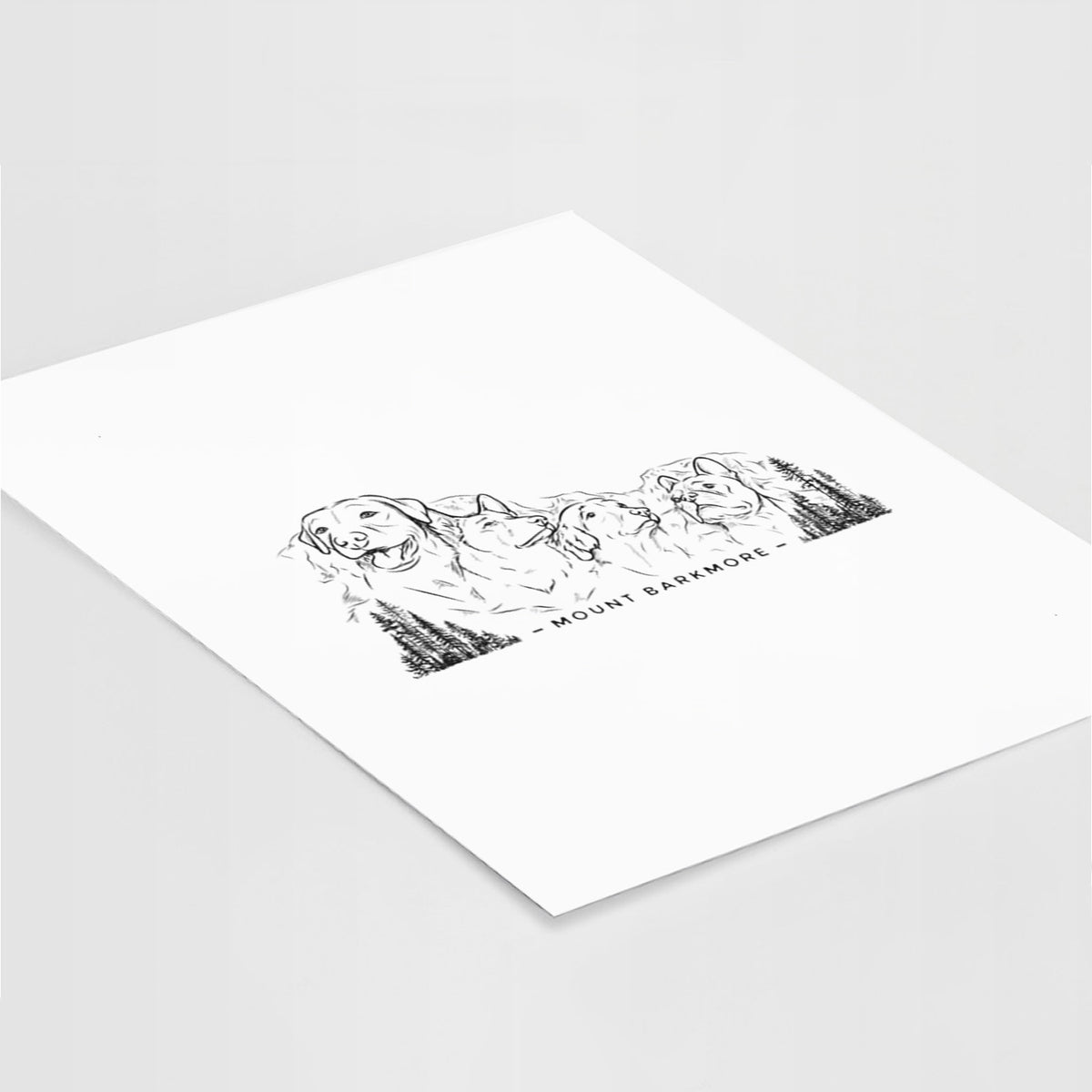 Art print of a black ink illustration of four dog faces carved into a mountain, with the words Mount Barkmore, lying at an angle on a white surface.