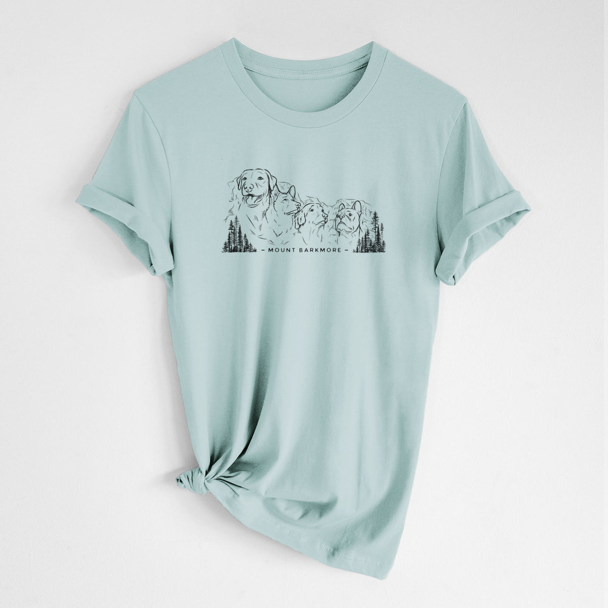 Dusty blue lightweight cotton t-shirt laid flat with the sleeves rolled, printed with a black ink illustration of four dog faces carved into a mountain, with the words Mount Barkmore.