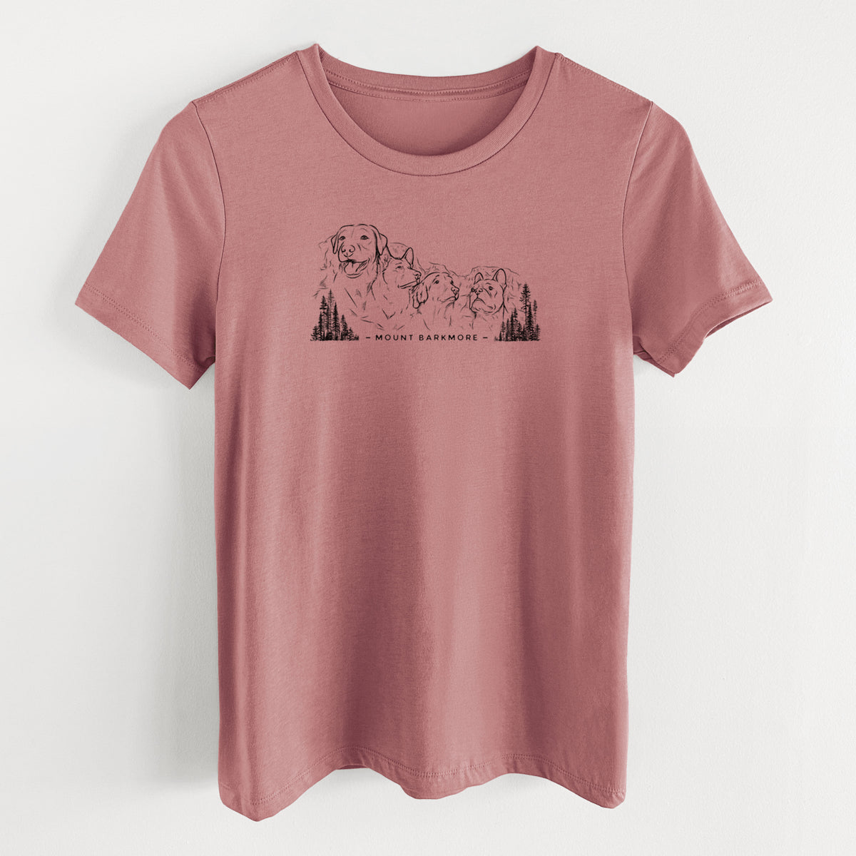 Mauve pink women's relaxed fit cotton t-shirt laid flat, printed with a black ink illustration of four dog faces carved into a mountain, with the words Mount Barkmore.