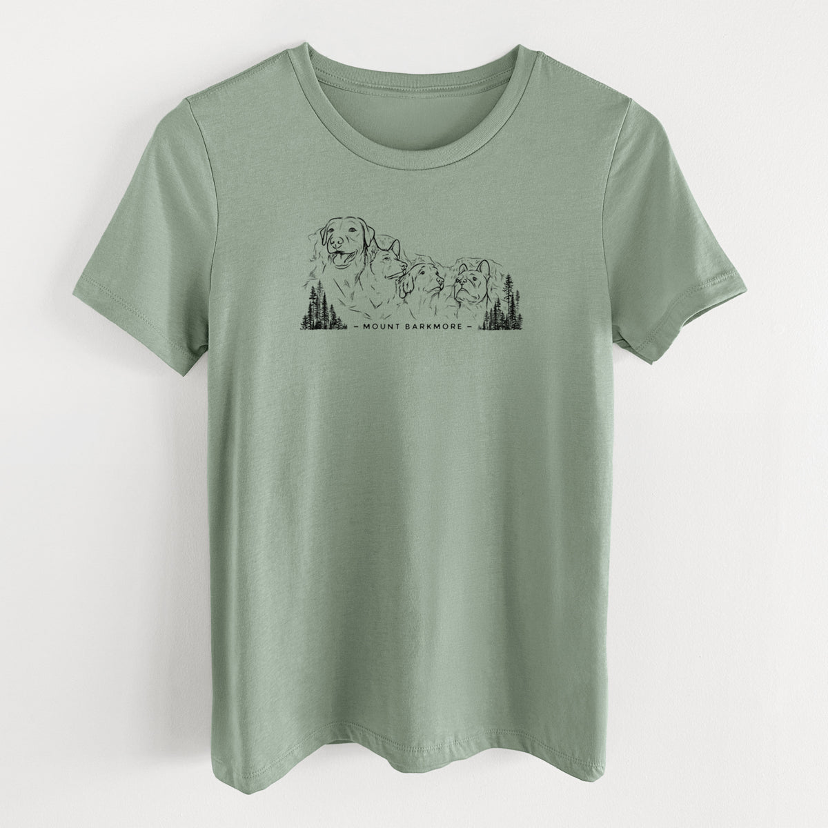 Sage green women's relaxed fit cotton t-shirt laid flat, printed with a black ink illustration of four dog faces carved into a mountain, with the words Mount Barkmore.