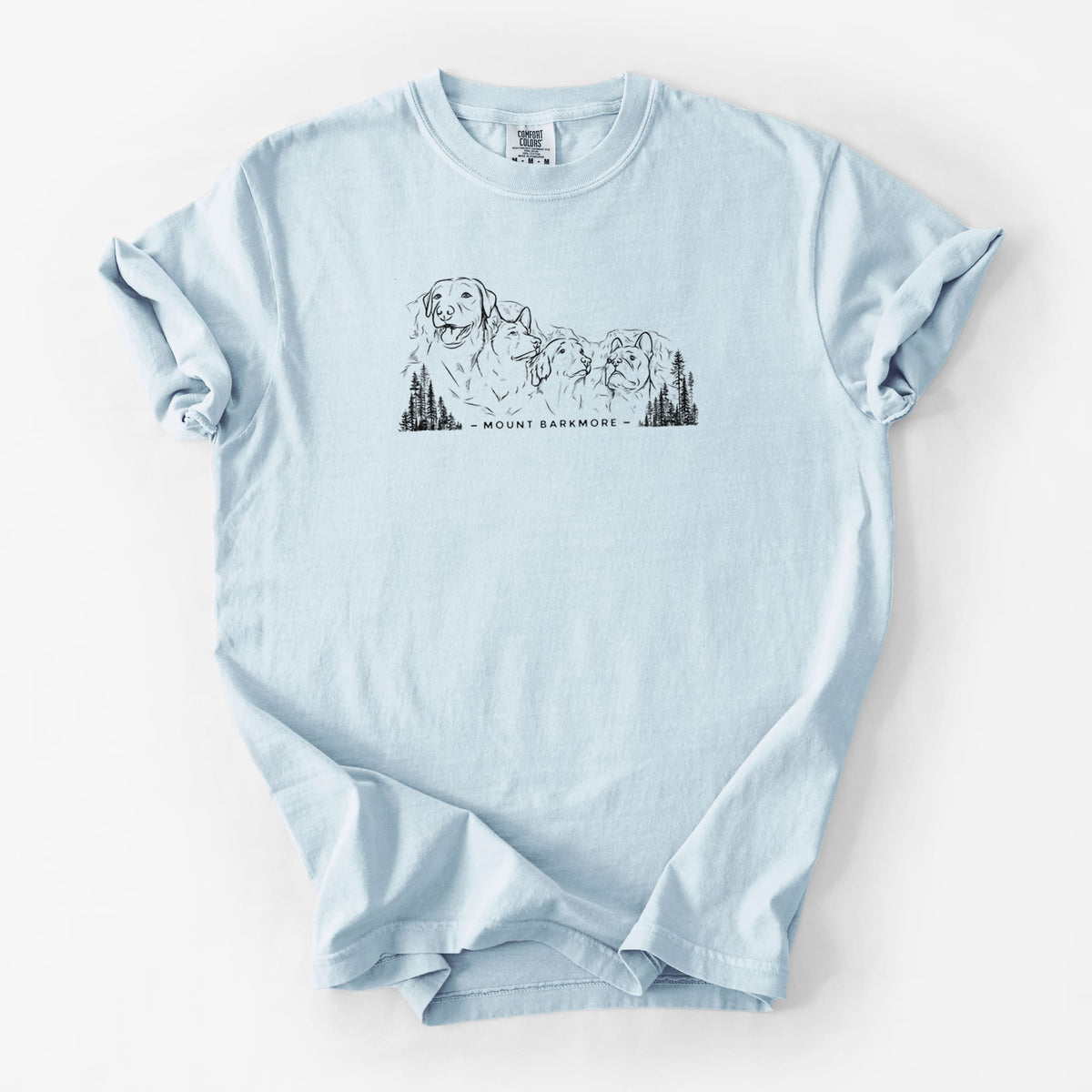 Chambray blue Comfort Colors t-shirt laid flat, printed with a black ink illustration of four dog faces carved into a mountain, with the words Mount Barkmore.