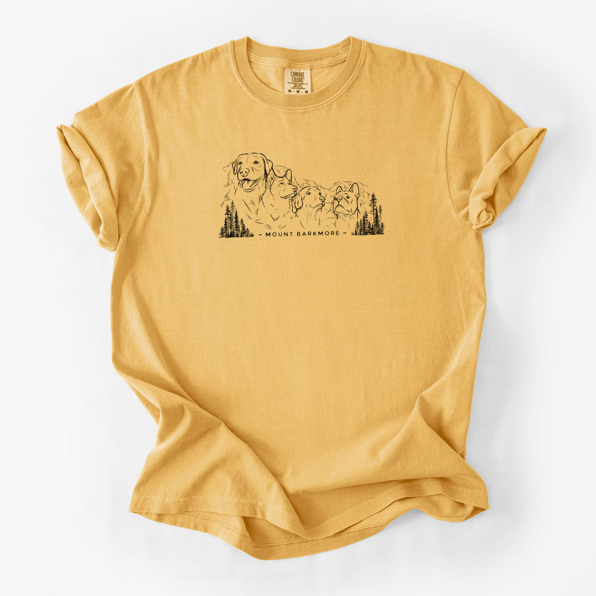 Golden wheat yellow Comfort Colors t-shirt laid flat, printed with a black ink illustration of four dog faces carved into a mountain, with the words Mount Barkmore.