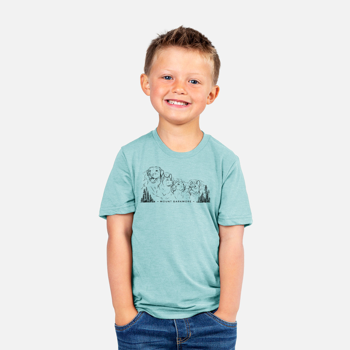 Smiling boy wearing a youth t-shirt printed with a black ink illustration of four dog faces carved into a mountain, with the words Mount Barkmore.