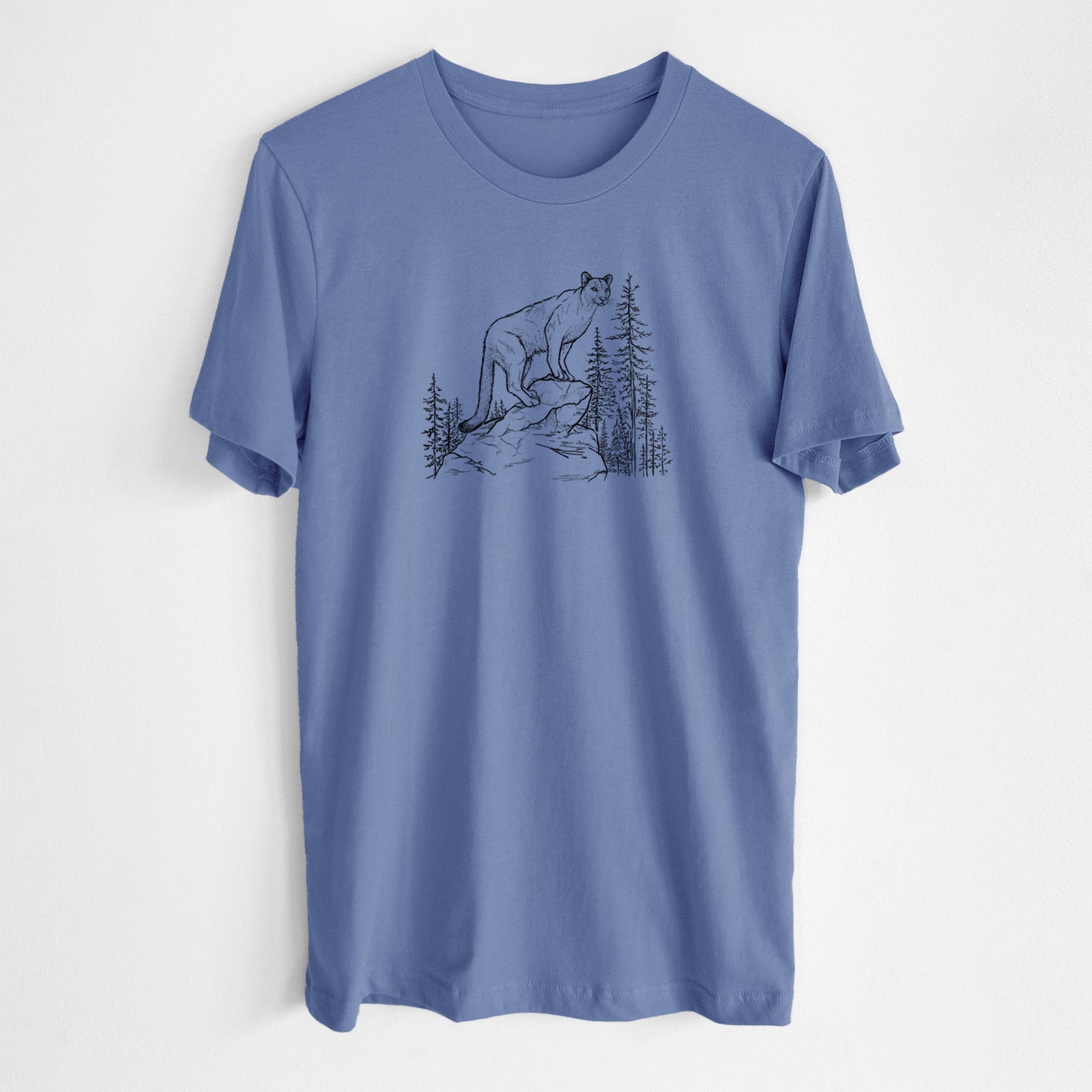Blue bell lightweight cotton t-shirt laid flat, printed with a black ink illustration of a mountain lion standing on a rocky ledge among pine trees.