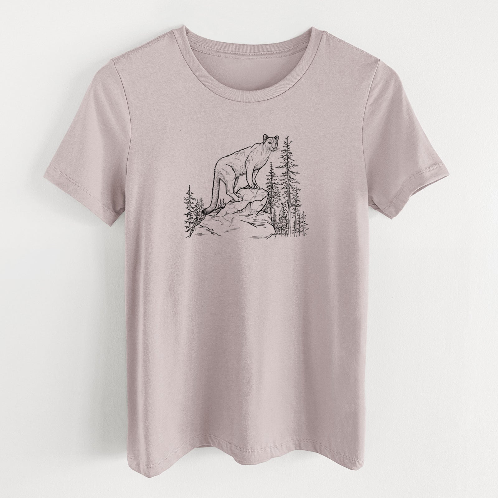 Pink gravel women's relaxed fit cotton t-shirt laid flat, printed with a black ink illustration of a mountain lion standing on a rocky ledge among pine trees.
