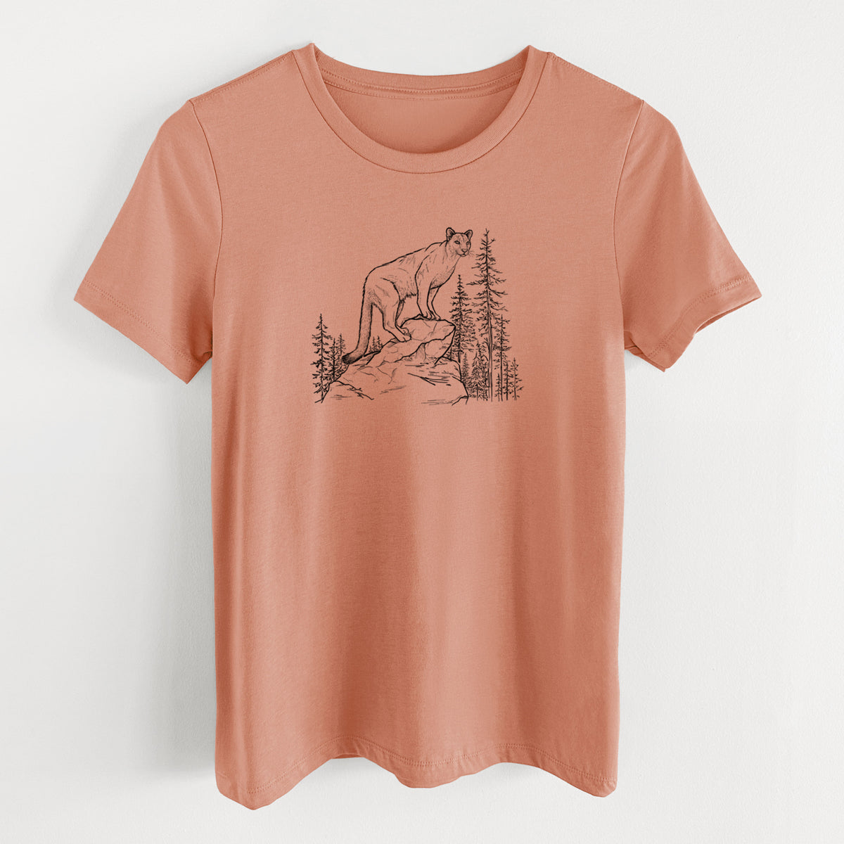 Terracotta orange women's relaxed fit cotton t-shirt laid flat, printed with a black ink illustration of a mountain lion standing on a rocky ledge among pine trees.