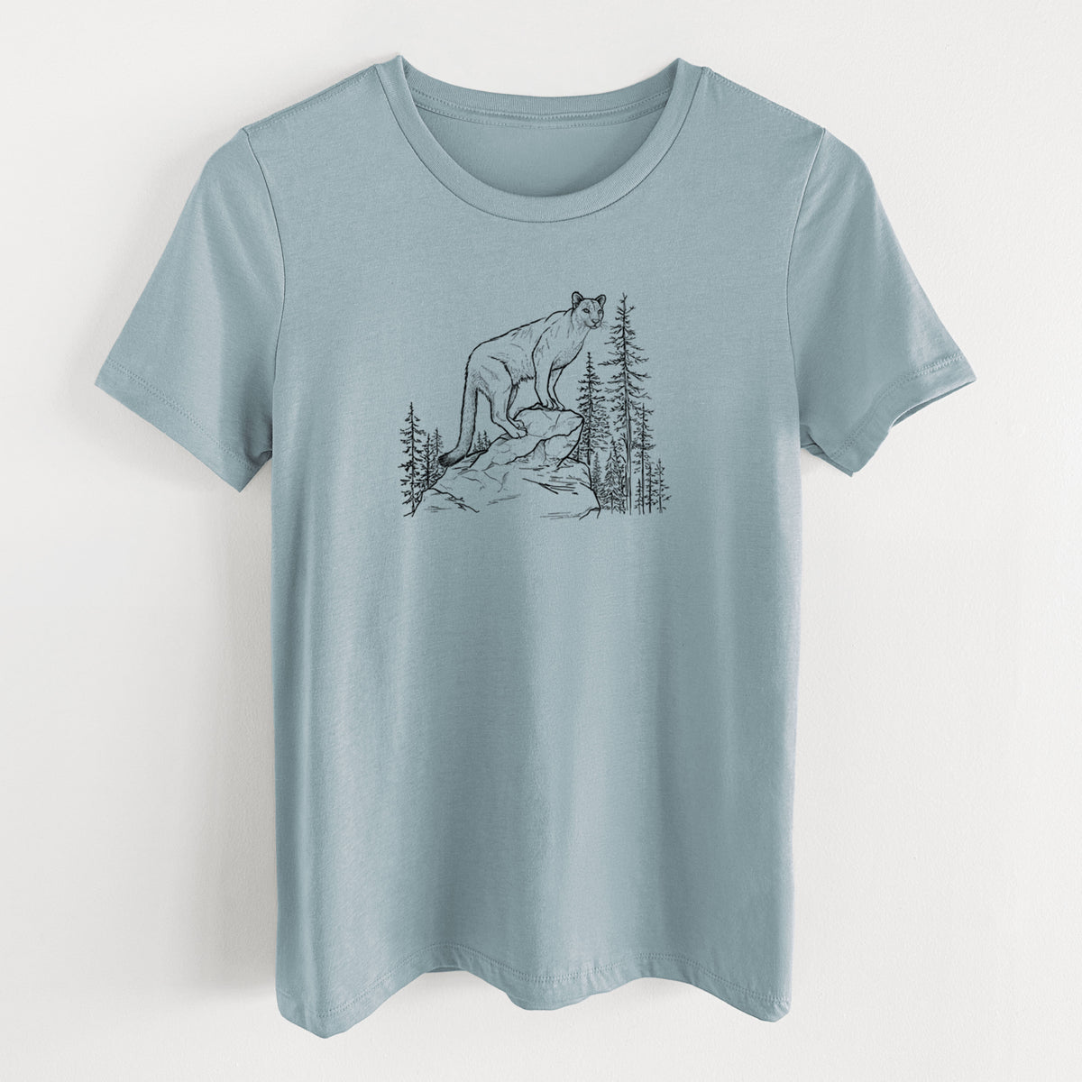 Vintage denim women's relaxed fit cotton t-shirt laid flat, printed with a black ink illustration of a mountain lion standing on a rocky ledge among pine trees.