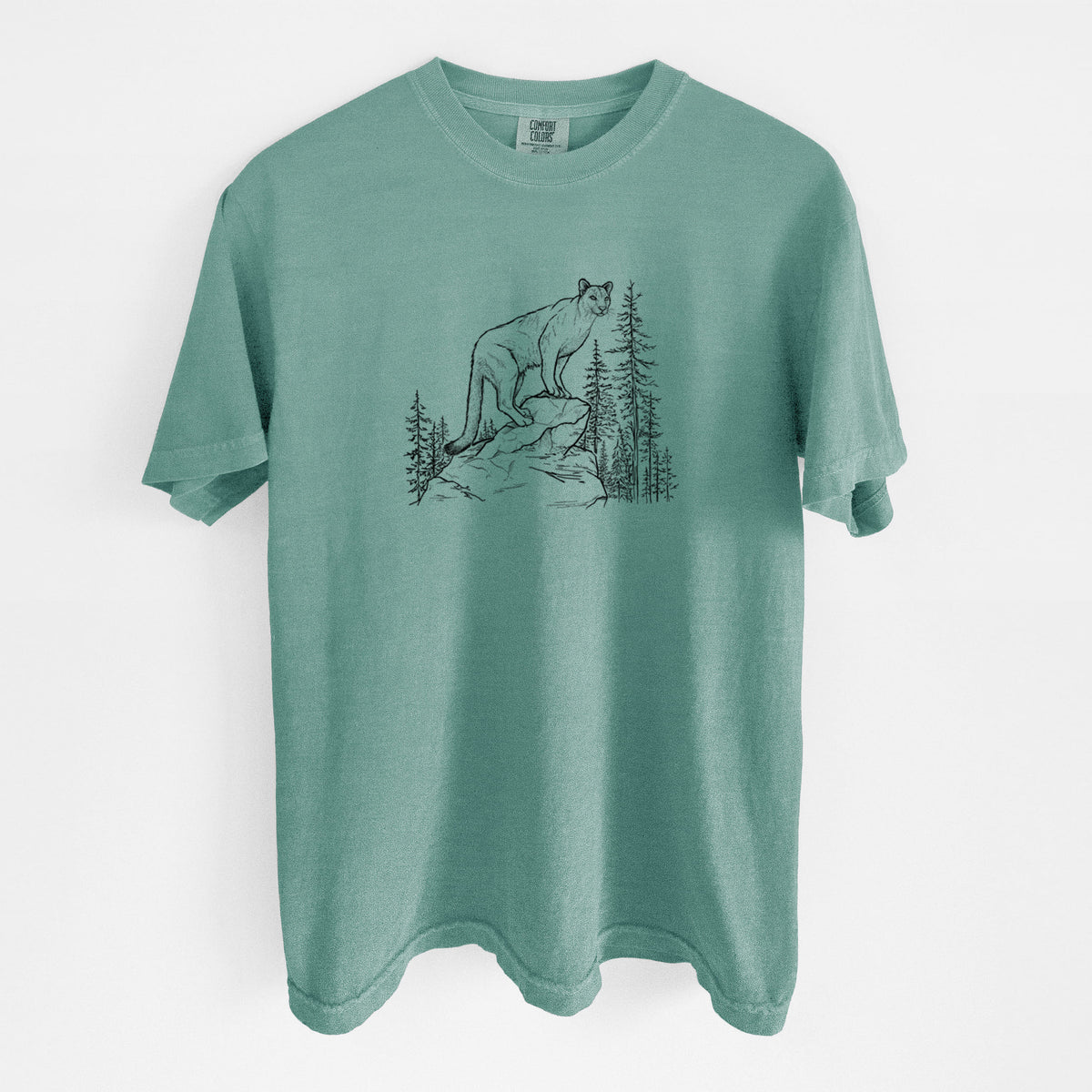 Reef green Comfort Colors t-shirt laid flat, printed with a black ink illustration of a mountain lion standing on a rocky ledge among pine trees.